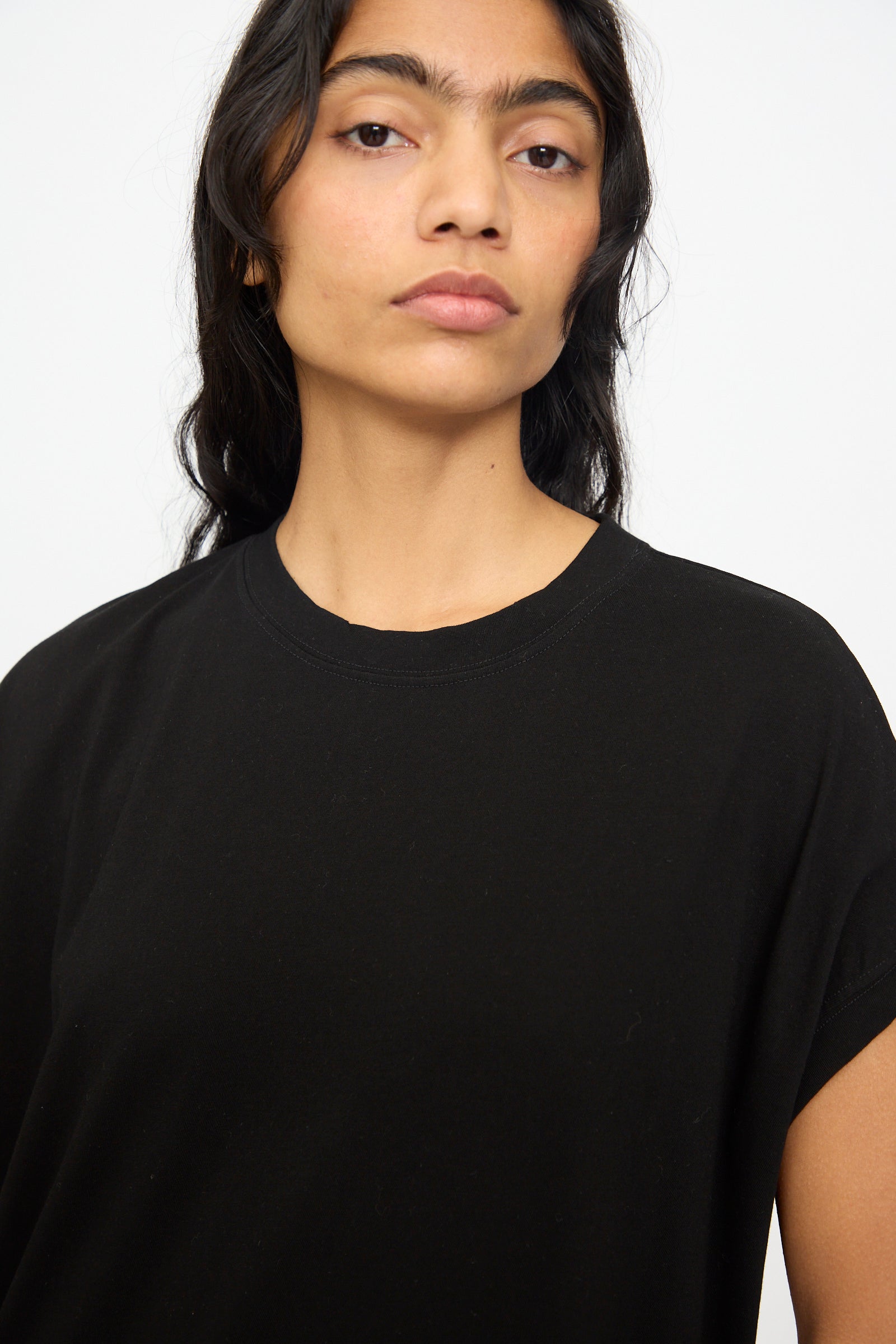 A person with long dark hair wears the Ichi Antiquités Cotton Sleeveless Dress in Black, standing against a light background and looking straight at the camera.