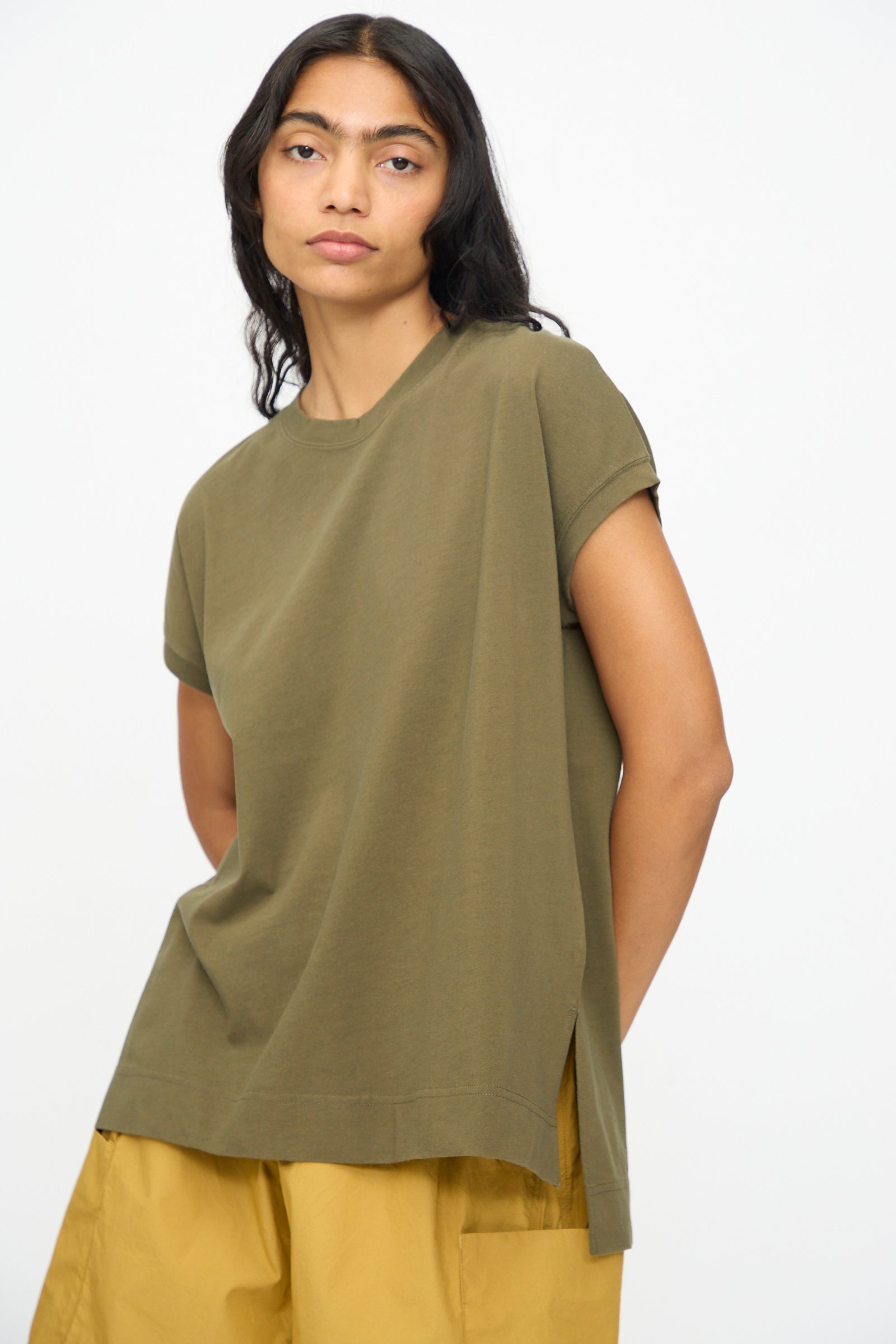 A person wearing the Ichi Antiquités Cotton Sleeveless Tee in Khaki and mustard yellow pants stands against a plain white background.