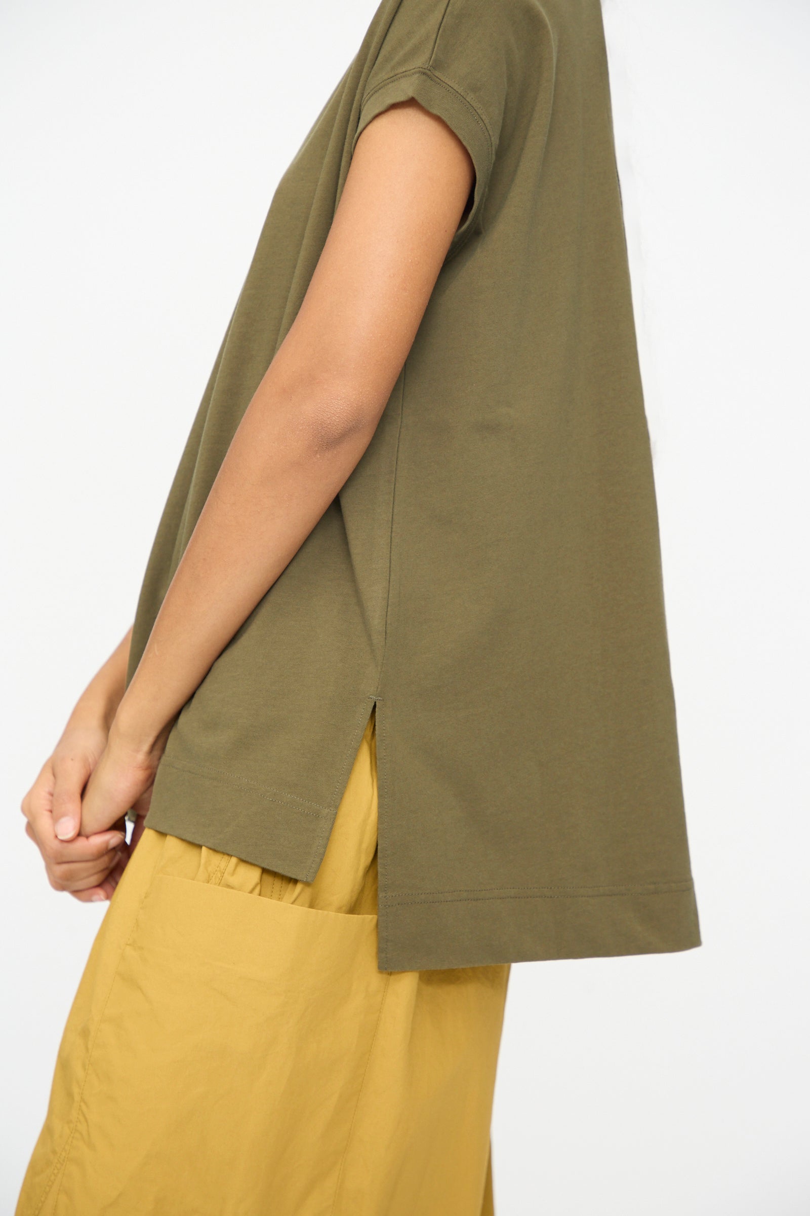 Model wears the Ichi Antiquités Cotton Sleeveless Tee in Khaki, paired with a mustard yellow skirt, standing against a plain white background.