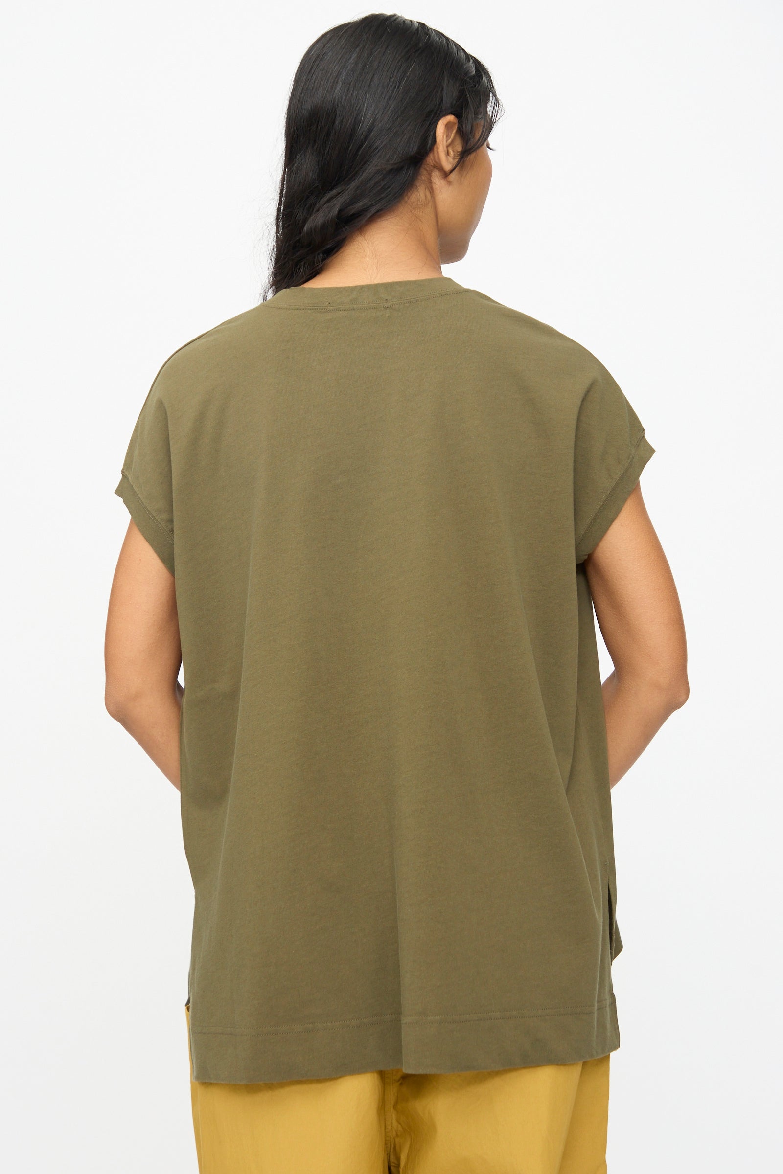 A person stands with their back to the camera, wearing the Ichi Antiquités Cotton Sleeveless Tee in Khaki and mustard yellow pants, set against a plain white background.