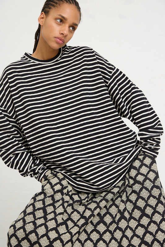 Woman wearing an Ichi Antiquités Cotton Stripe Loose Pullover in Black and Natural and patterned skirt, posing with one hand on her hip.