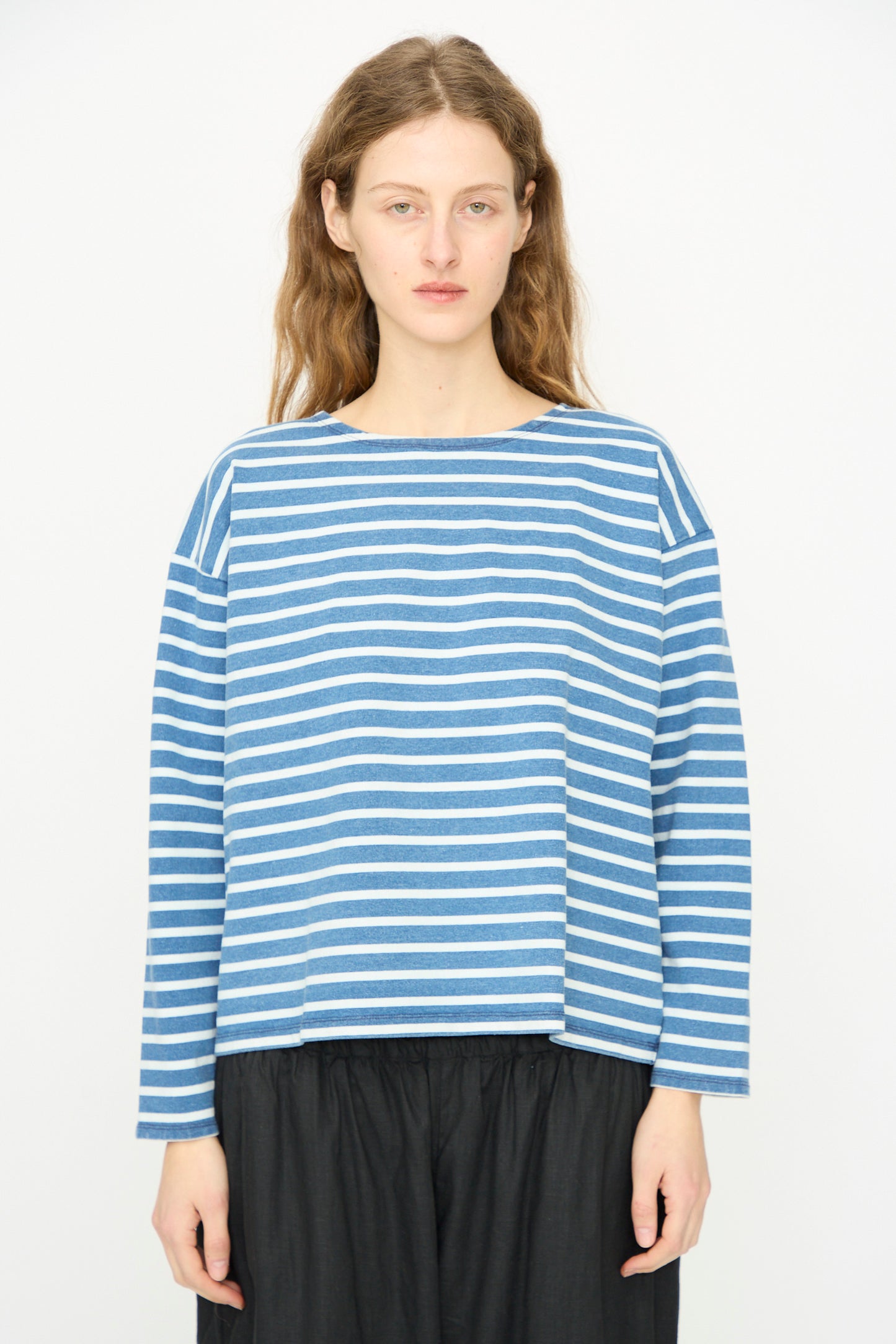 A person stands facing forward, wearing the Ichi Antiquités Cotton Stripe Pullover in Blue and White with black pants against a plain white background.