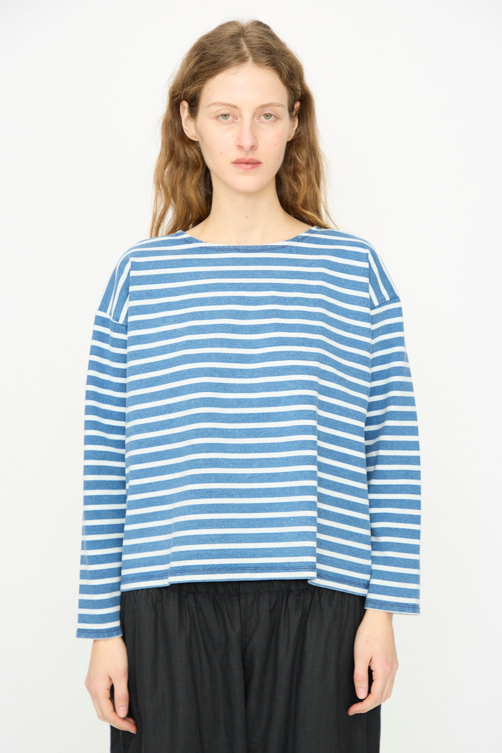 A person stands facing forward, wearing the Ichi Antiquités Cotton Stripe Pullover in Blue and White with black pants against a plain white background.