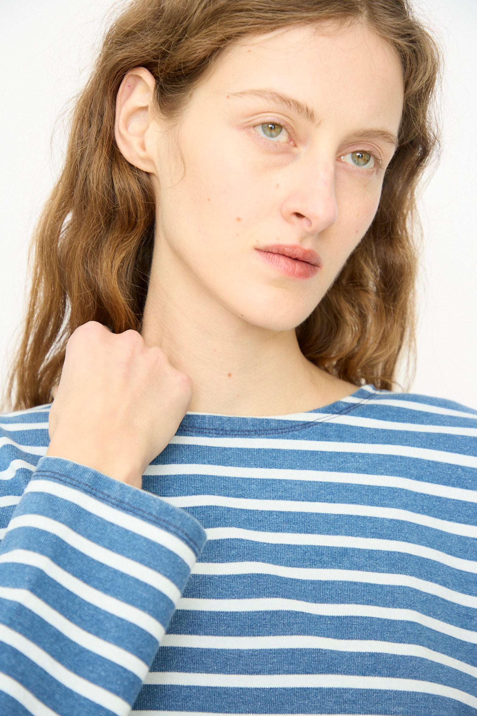A person with long light brown hair wears the Ichi Antiquités Cotton Stripe Pullover in Blue and White, made in Japan, looking slightly to the side with a neutral expression.