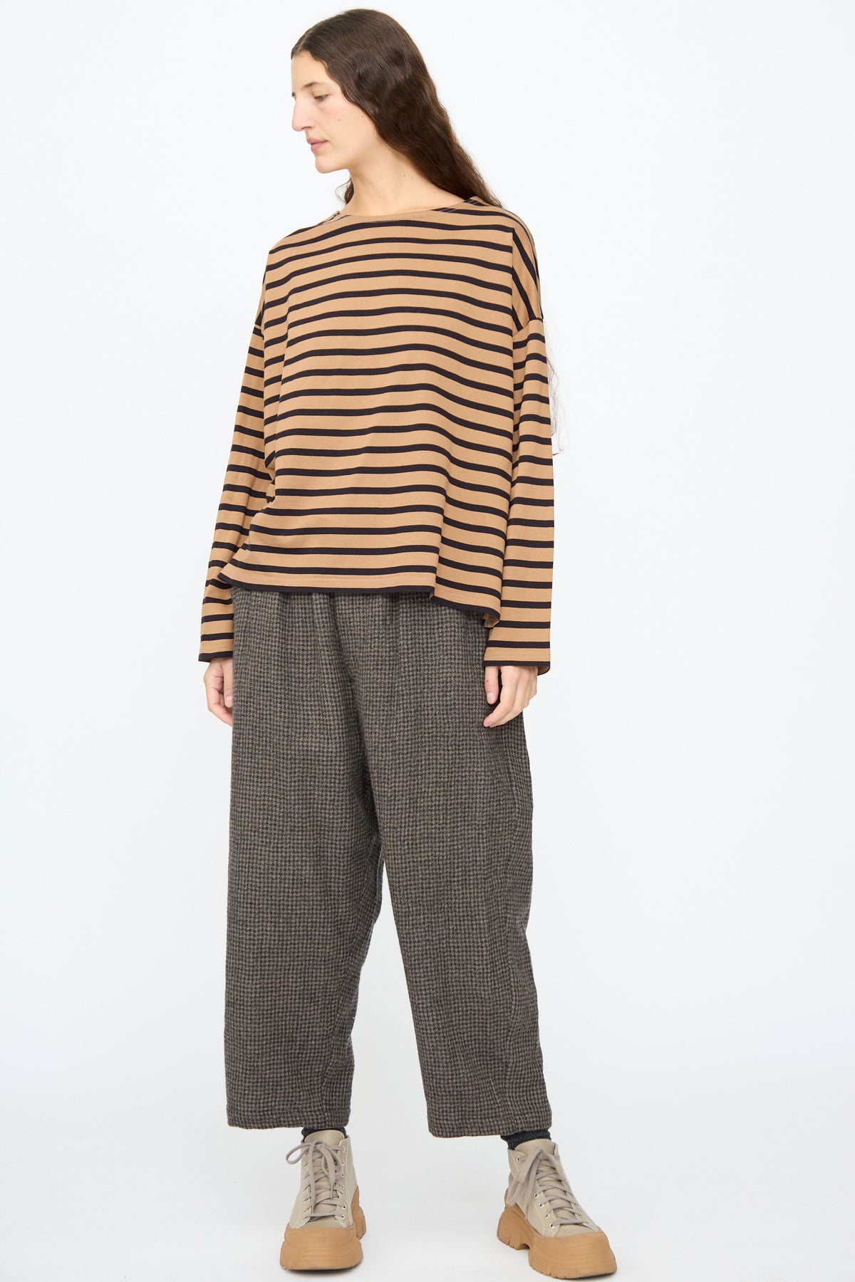 A person wearing an Ichi Antiquités Cotton Stripe Pullover in Mocha and Navy, dark patterned trousers, and tan lace-up sneakers.