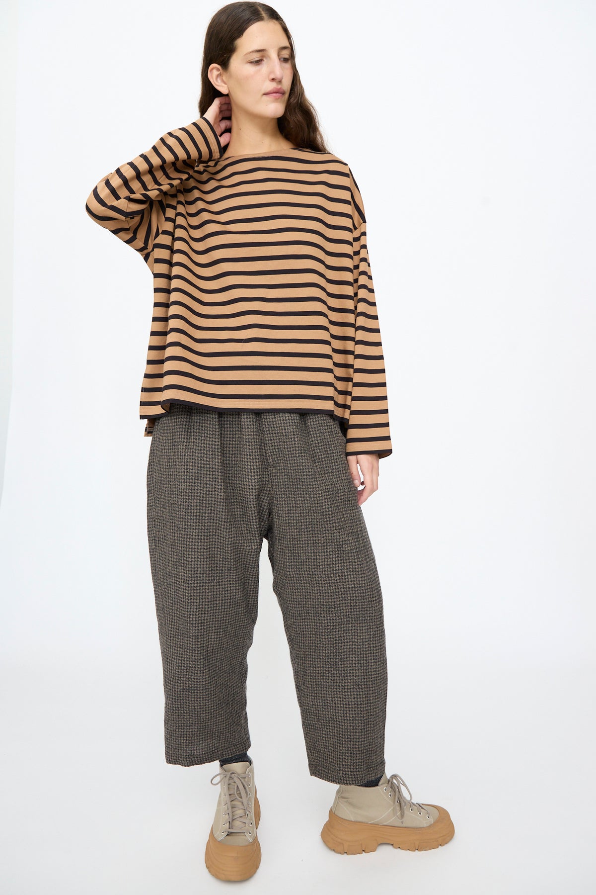 A person wears an Ichi Antiquités Cotton Stripe Pullover in Mocha and Navy, dark patterned trousers, and tan lace-up sneakers.