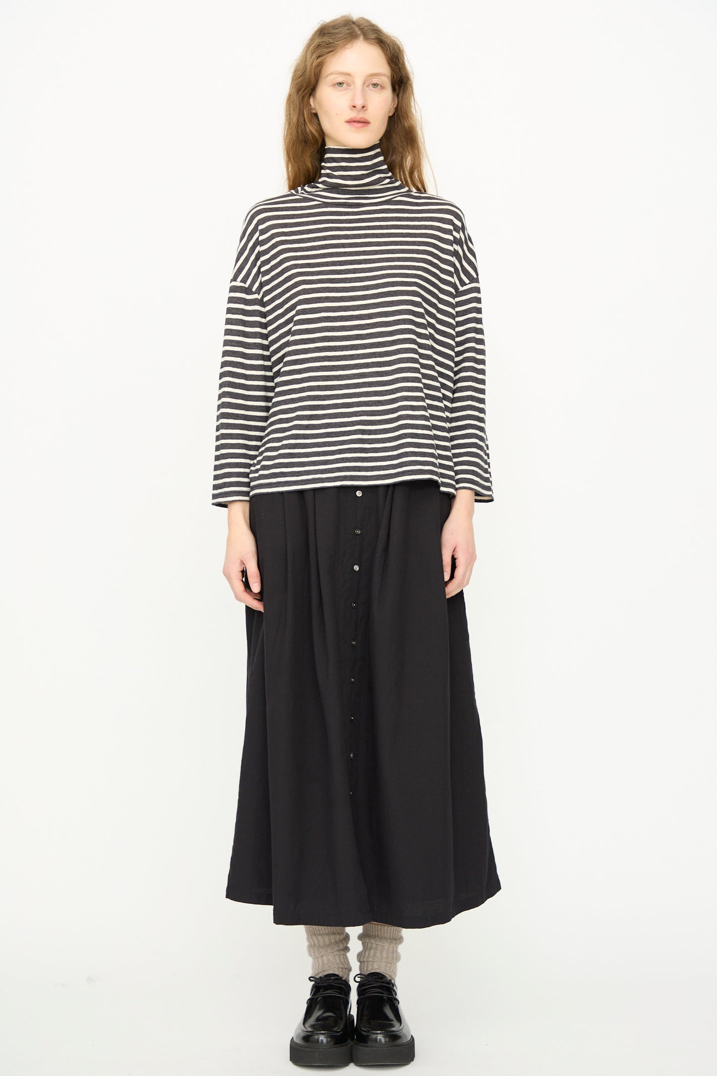 Person stands against a white background, wearing Ichi Antiquités’ Cotton Stripe Turtleneck in Charcoal.