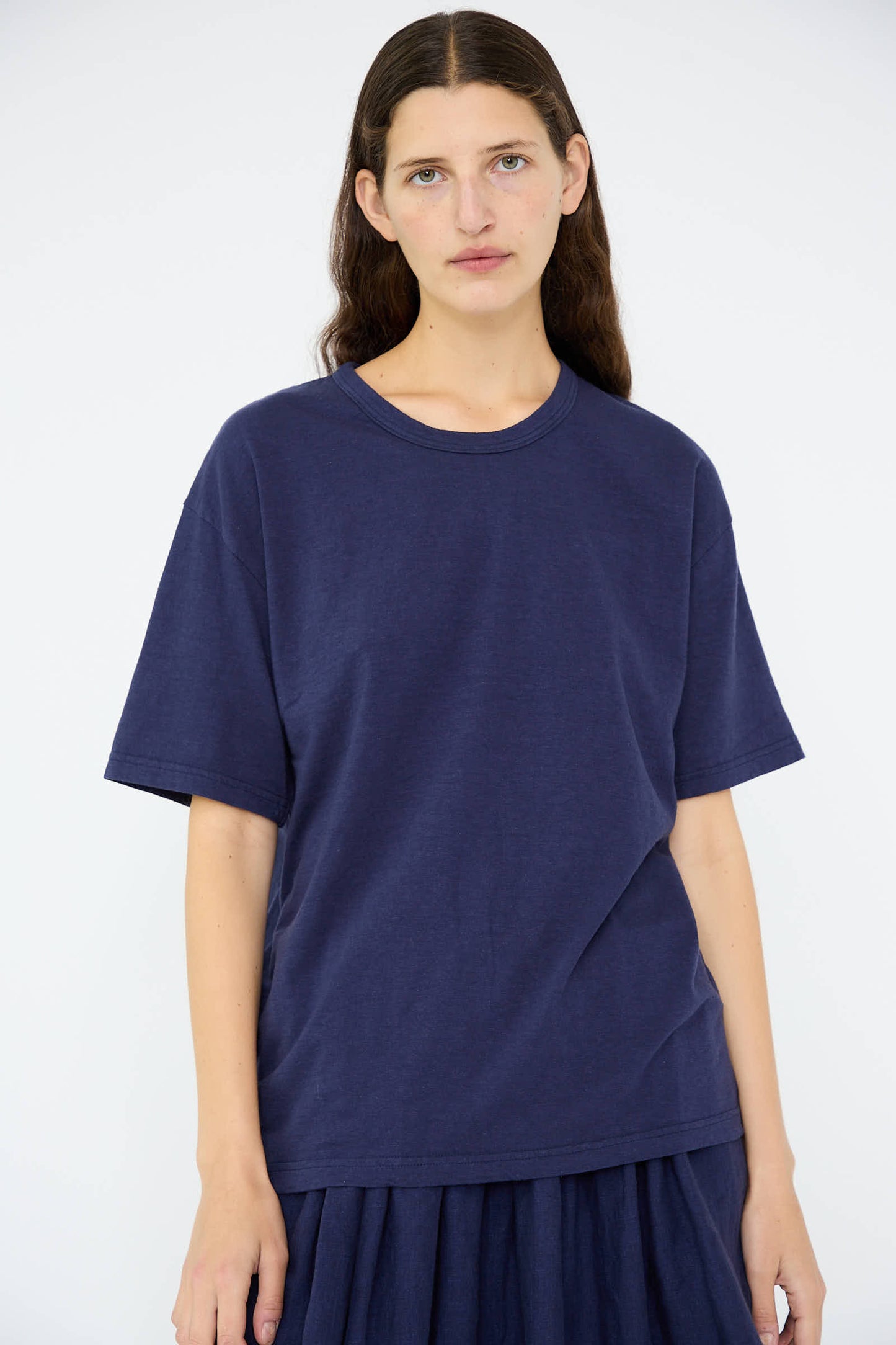 A person with long brown hair wears the Cotton T-Shirt in Navy by Ichi Antiquités, paired with a matching skirt, both made of medium weight cotton, standing against a plain white background.