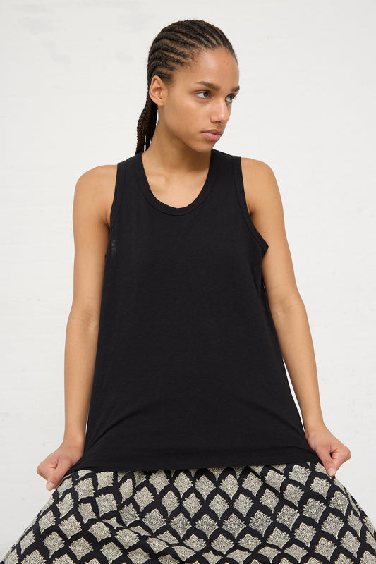 A person wearing an Ichi Antiquités black cotton tank top and patterned bottoms, standing against a white background.