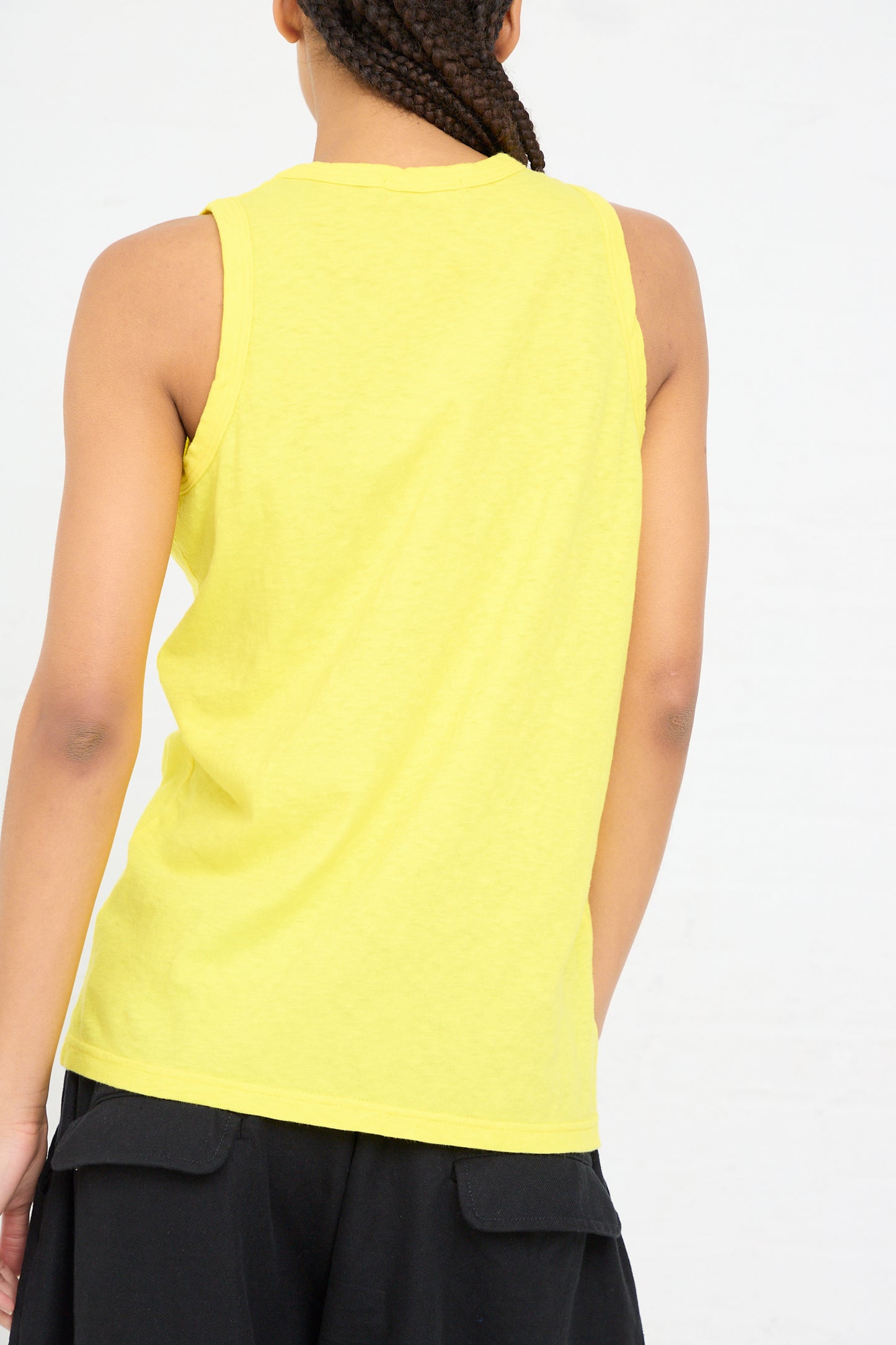 Woman seen from behind wearing a lightweight Cotton Tank in Lemon by Ichi Antiquités and black pants.