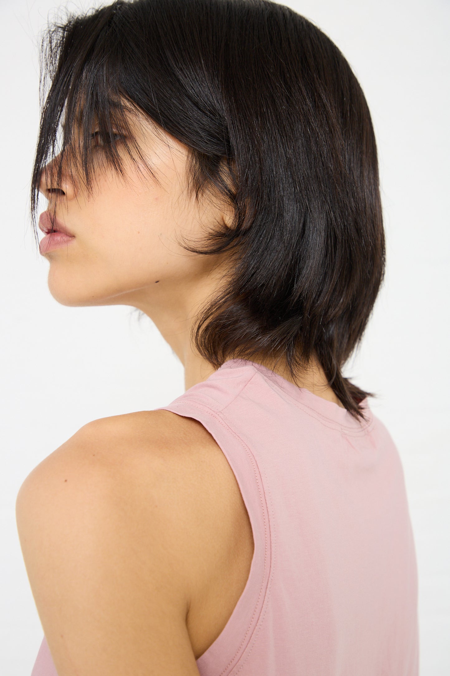 Profile view of a person with short, dark hair wearing a Cotton Tank in Pink by Ichi Antiquités, looking to the left.