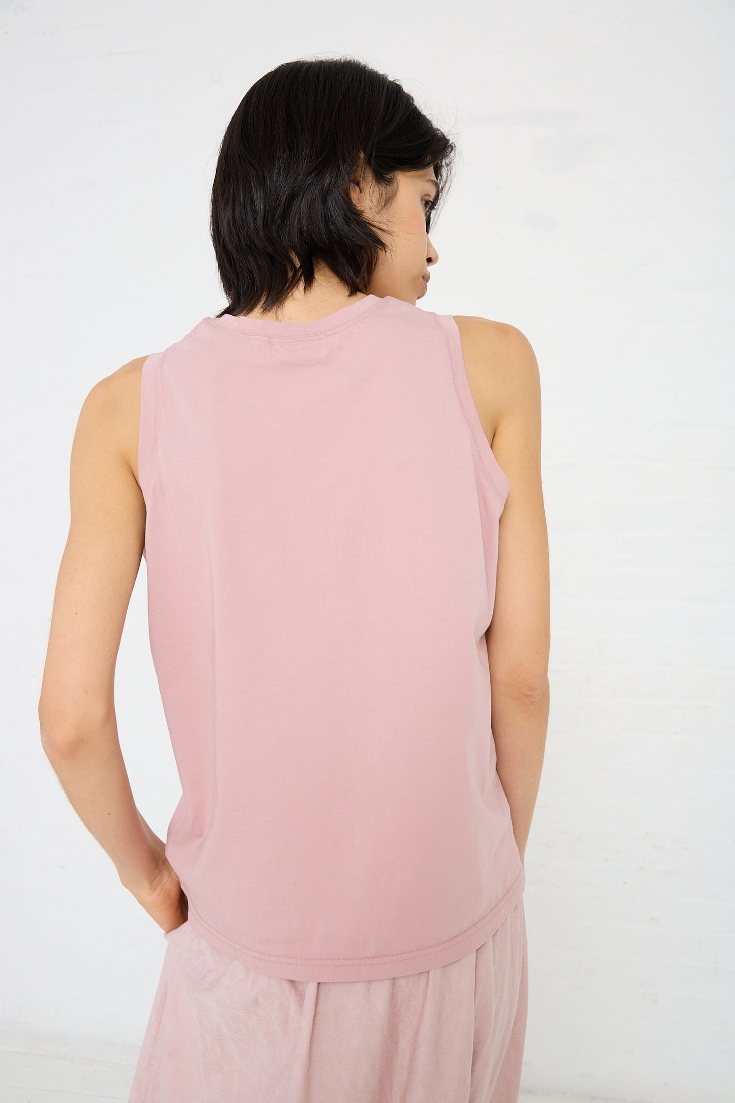 A person with short dark hair, wearing an Ichi Antiquités Cotton Tank in Pink and matching bottoms made of lightweight cotton, is standing with their back to the camera against a plain white background.