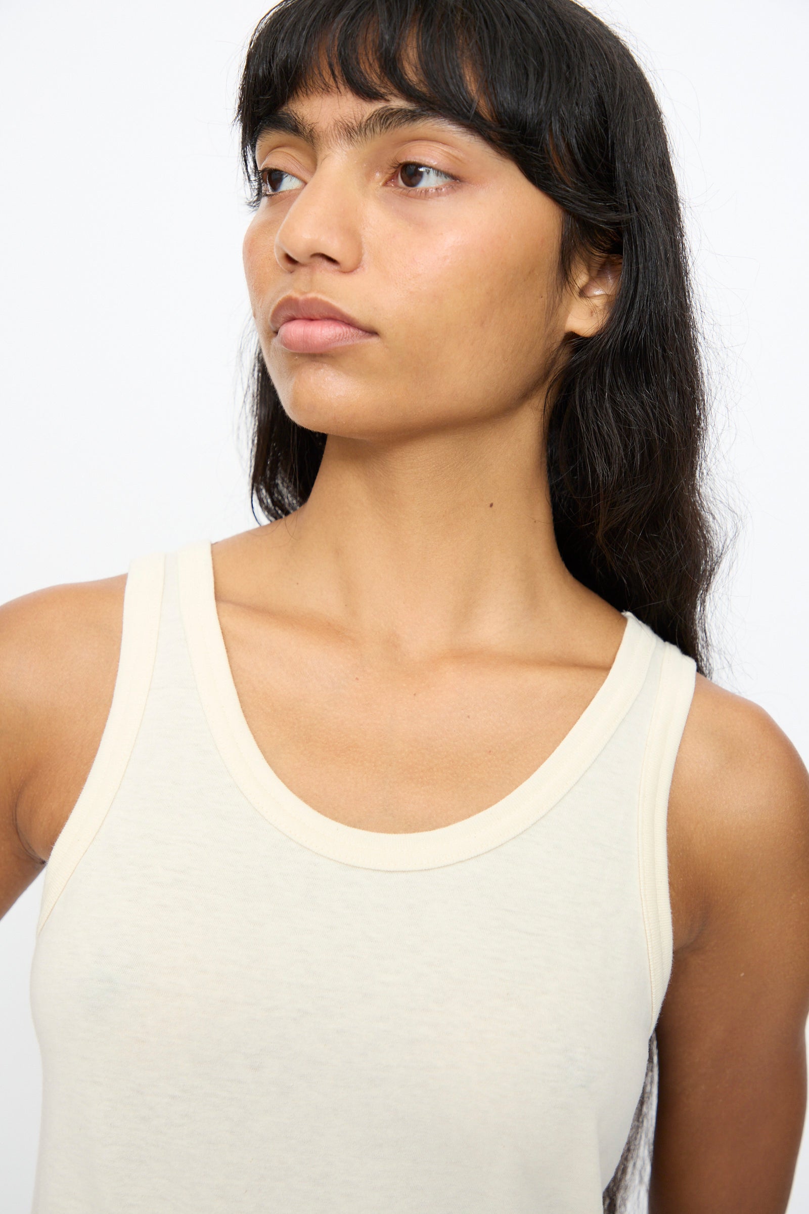 A person with long dark hair wears the Ichi Antiquités Cotton Tank Top in Natural, looking to the side against a plain background.