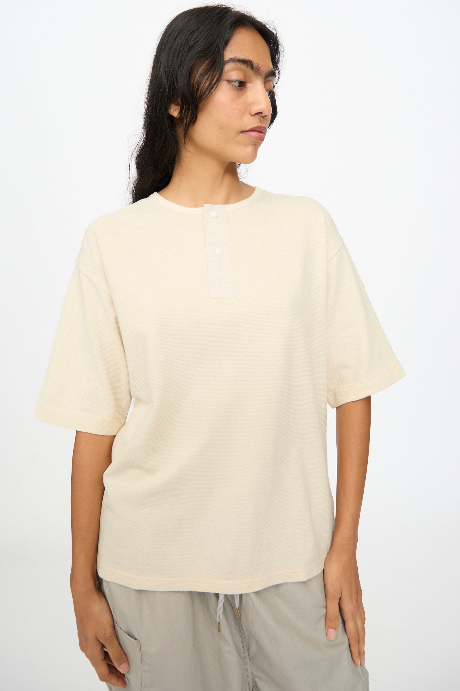 A person wears the Ichi Antiquités Cotton Thermal Henley Neck Pullover in Ivory, paired with light gray drawstring pants, standing against a plain white background.