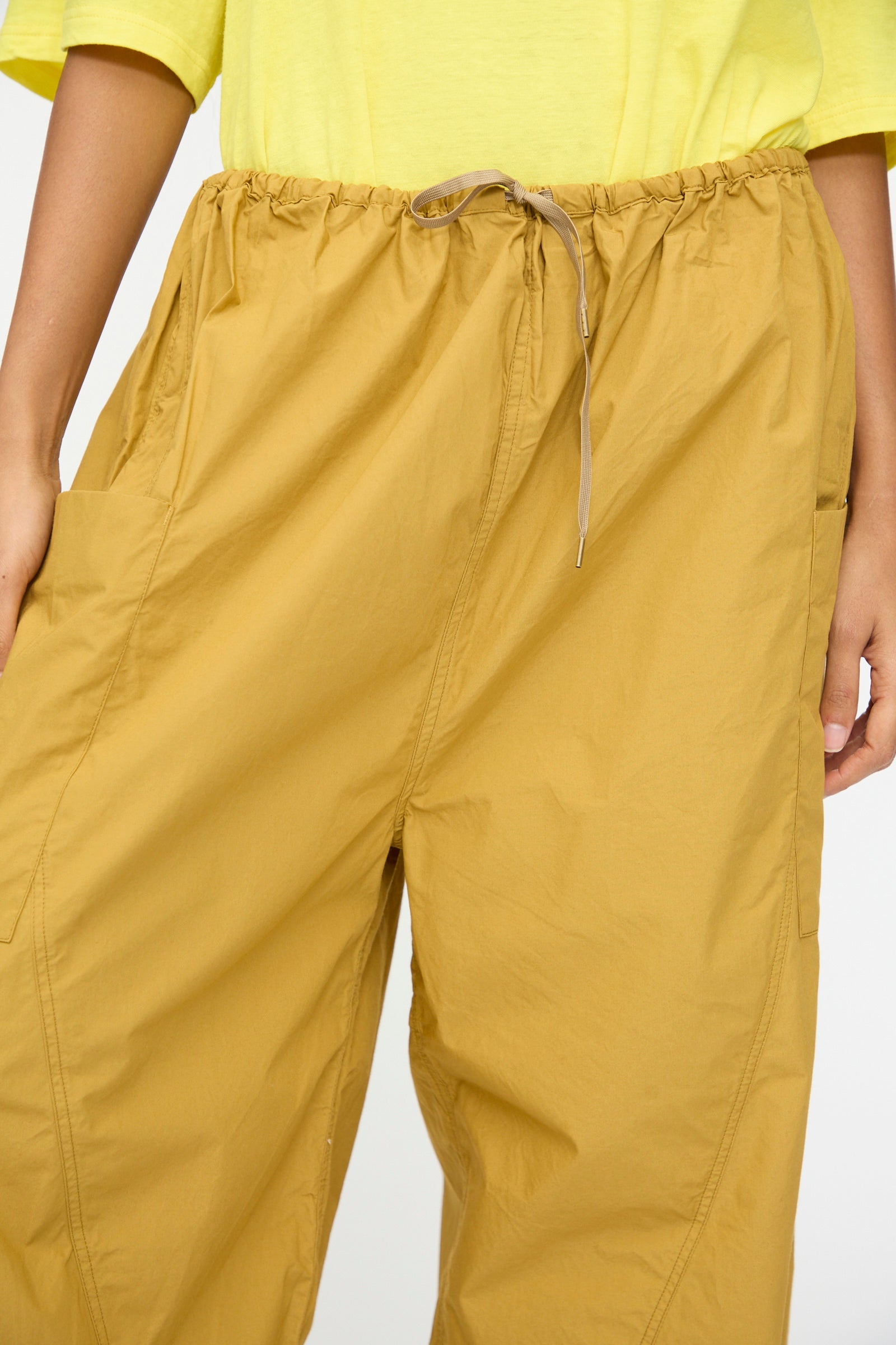 A person wears Ichi Antiquités Cotton Typewriter Pants in mustard with an elastic waist, paired with a light yellow top, shown from mid-torso to upper thighs.