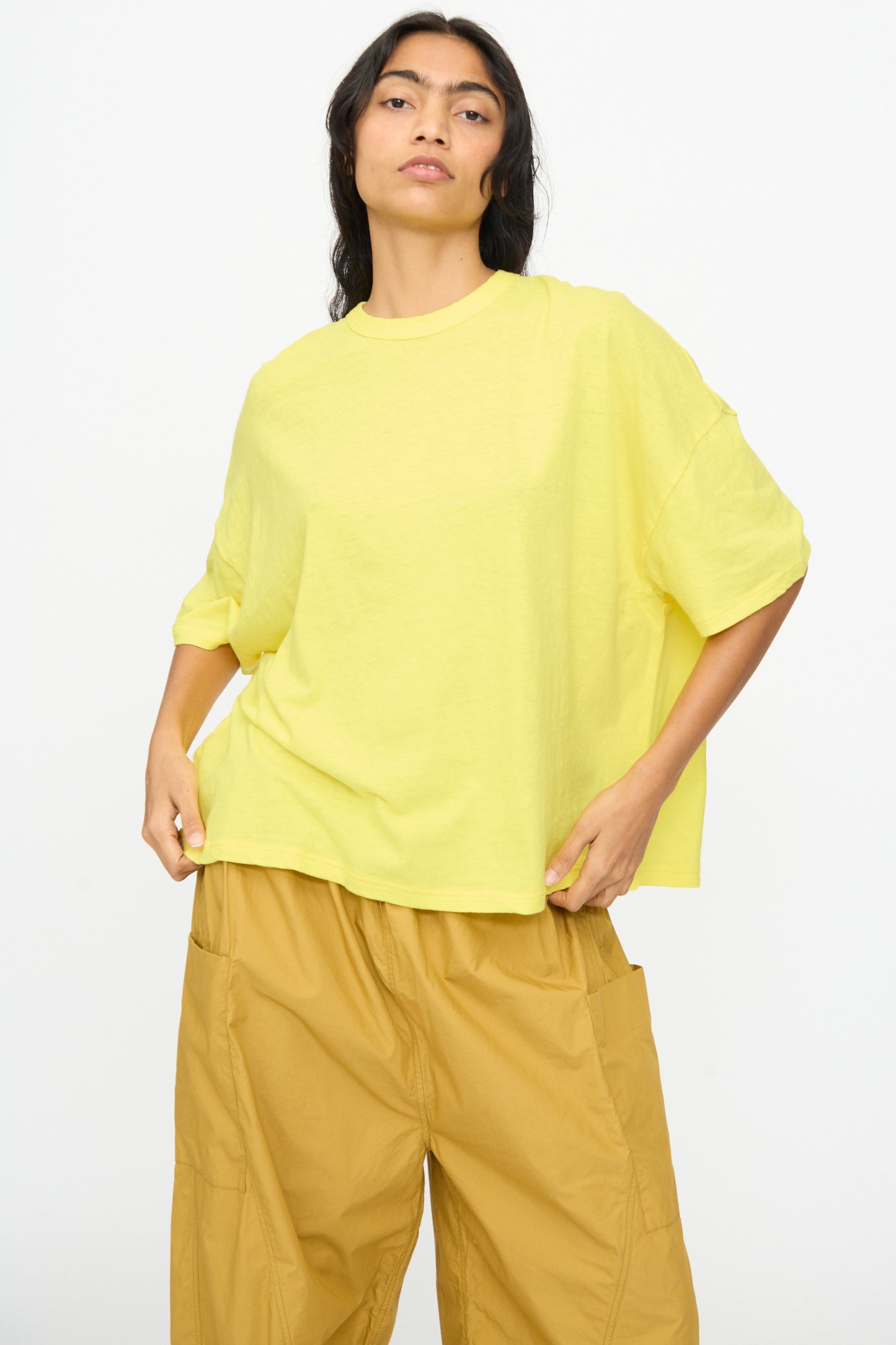 A person wears the Ichi Antiquités Cotton Wide Tee in Yellow with tan wide-leg pants, standing against a plain white background.