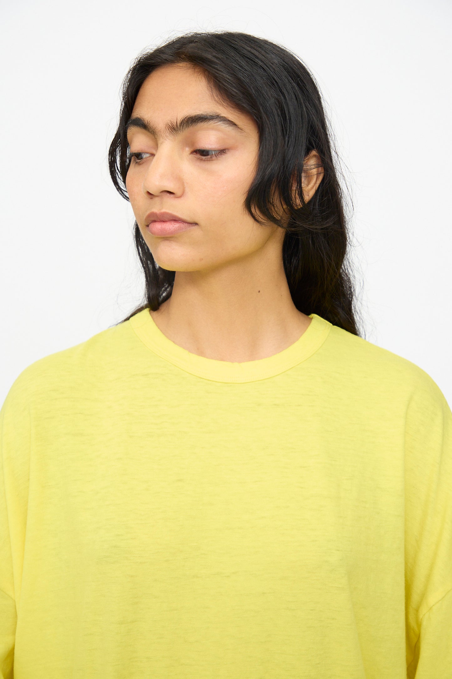 A person with long dark hair models the Ichi Antiquités Cotton Wide Tee in yellow, gazing to their left against a plain white background.