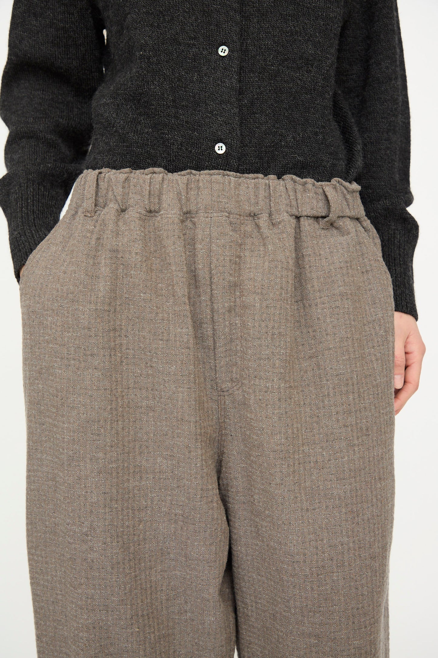 A person wearing a black buttoned sweater and the Cotton Wool Sucker Pant in Mocha by Ichi Antiquités—high-waisted, relaxed fit beige pants with an elastic waistband.