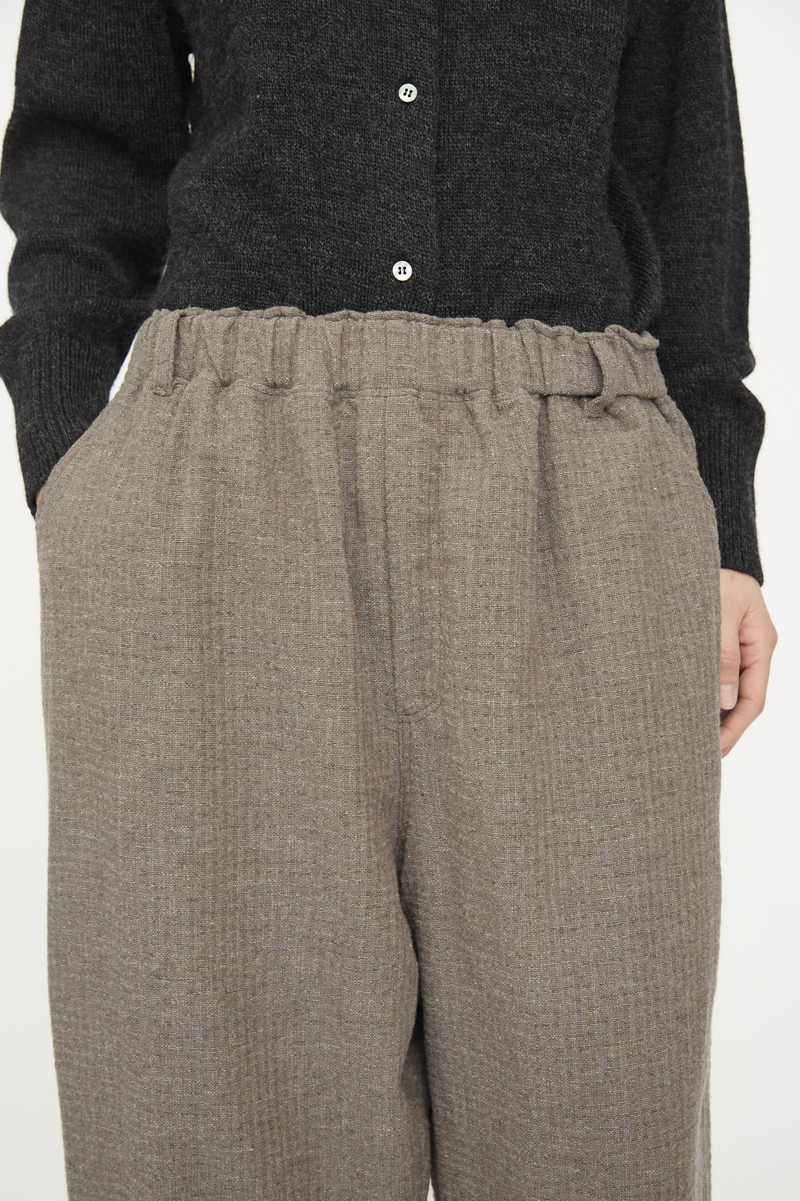 A person wearing a black buttoned sweater and the Cotton Wool Sucker Pant in Mocha by Ichi Antiquités—high-waisted, relaxed fit beige pants with an elastic waistband.