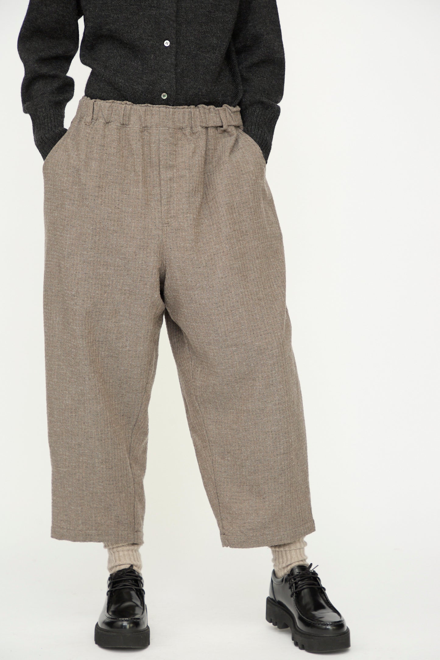 Model wears Ichi Antiquités' Cotton Wool Sucker Pant in Mocha—relaxed fit, high-waisted wide-leg style—paired with a dark shirt, beige socks, and black shoes, standing against a plain white background.