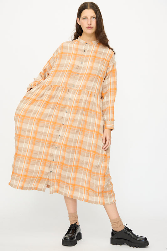 A woman stands against a white background wearing the Ichi Antiquités Cotton Wool Tartan Check Dress in Orange with buttons down the front, paired with black platform shoes.
