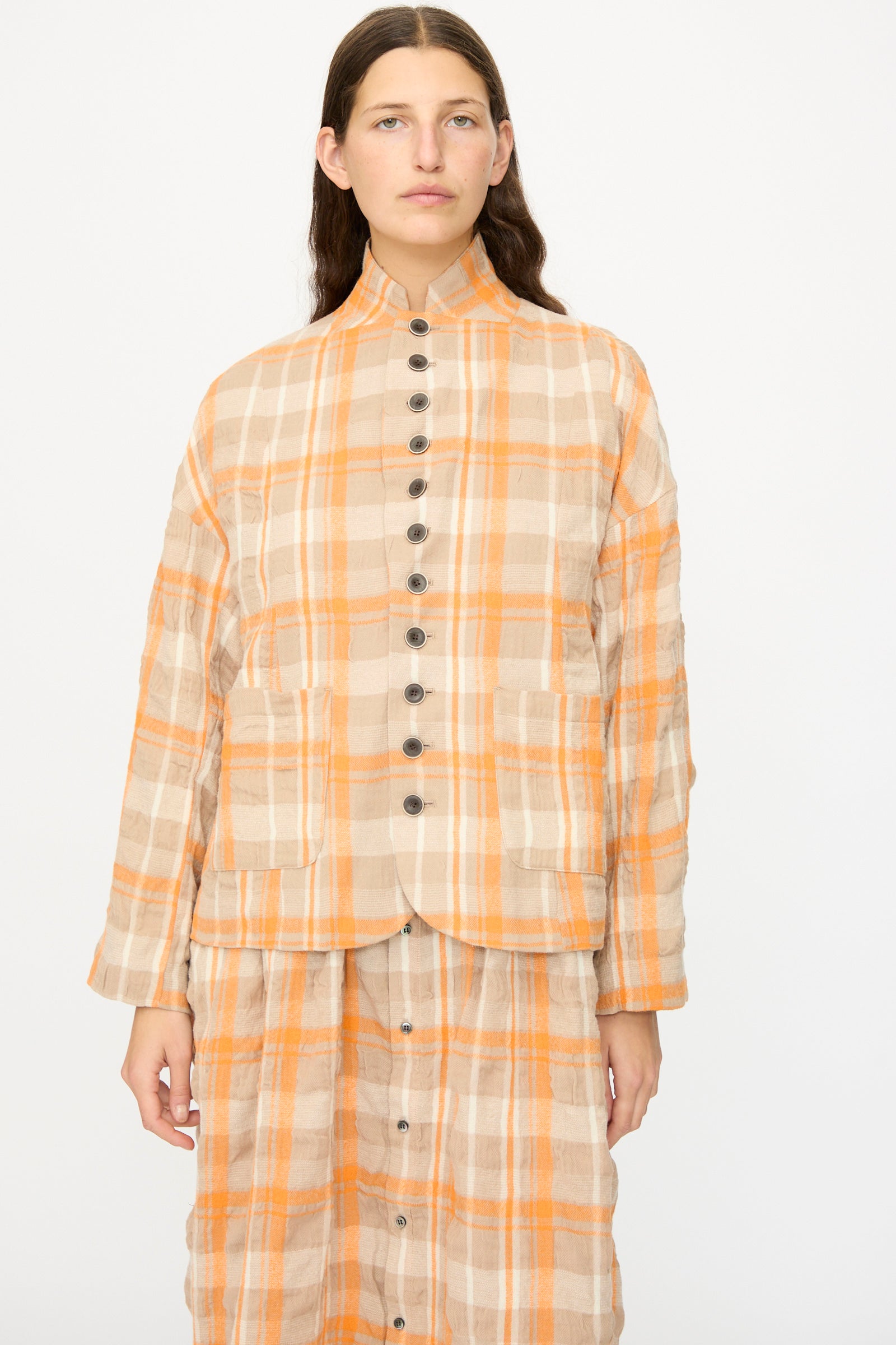 A woman wears the Ichi Antiquités Cotton Wool Tartan Check Jacket in Orange, paired with a matching skirt, standing against a plain white background.