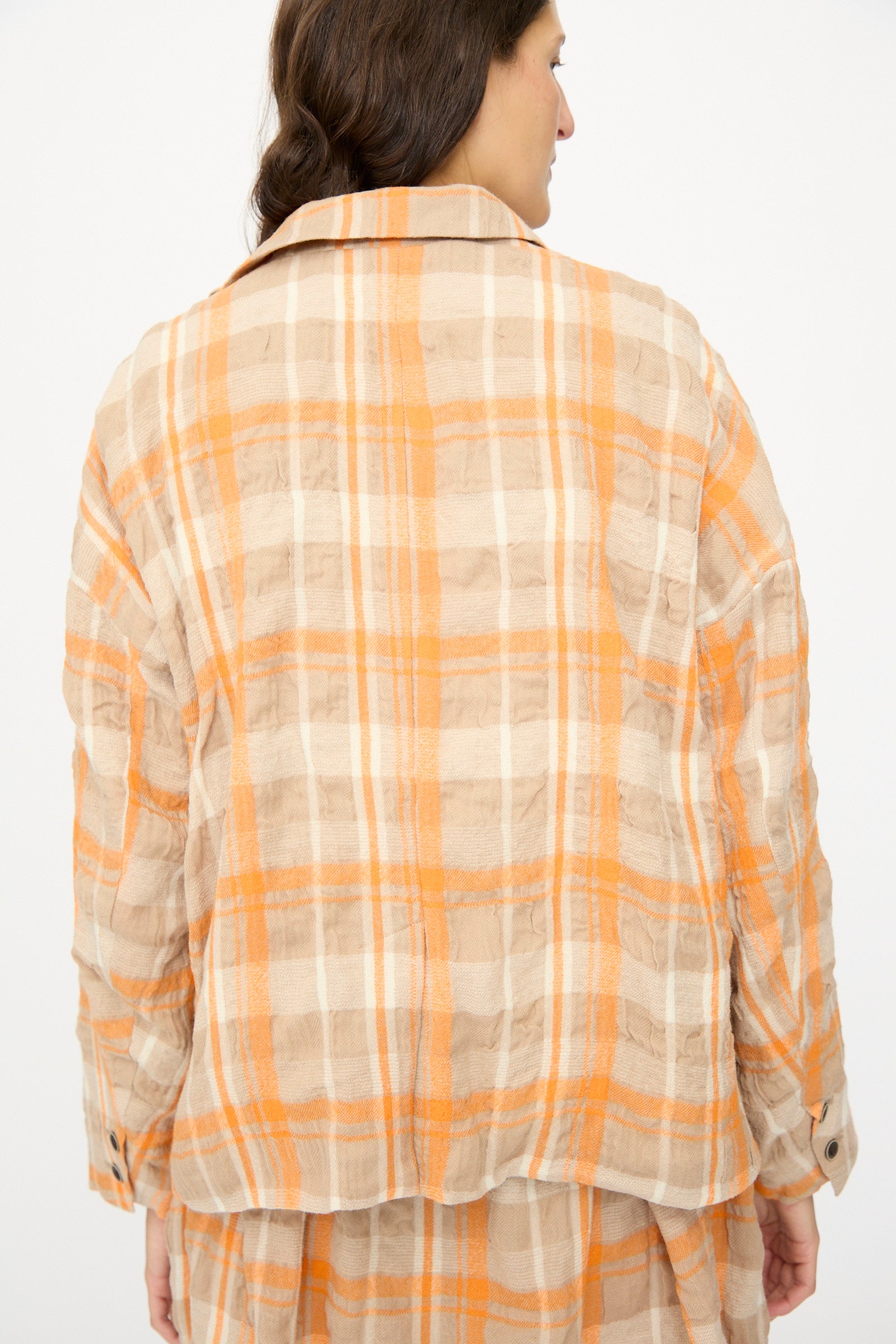 A person wearing the Ichi Antiquités Cotton Wool Tartan Check Jacket in Orange is shown from the back, head turned slightly to the side against a plain background.