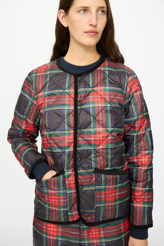 A woman models the Ichi Antiquités Down Jacket in Black Tartan, featuring black corduroy trim, standing slightly to the side with one hand in a pocket against a plain background.