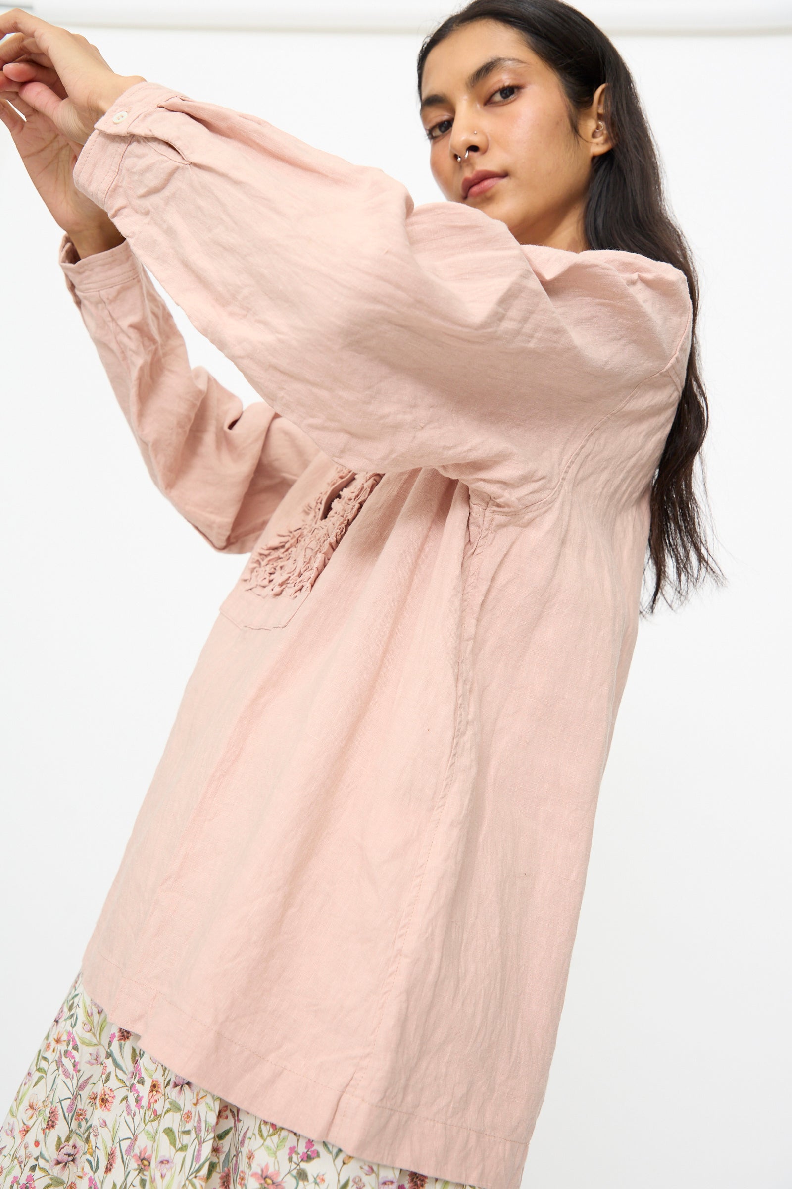 A woman in the Ichi Antiquités French Linen Shirt in Pink stands against a plain white background, paired with a floral patterned skirt.