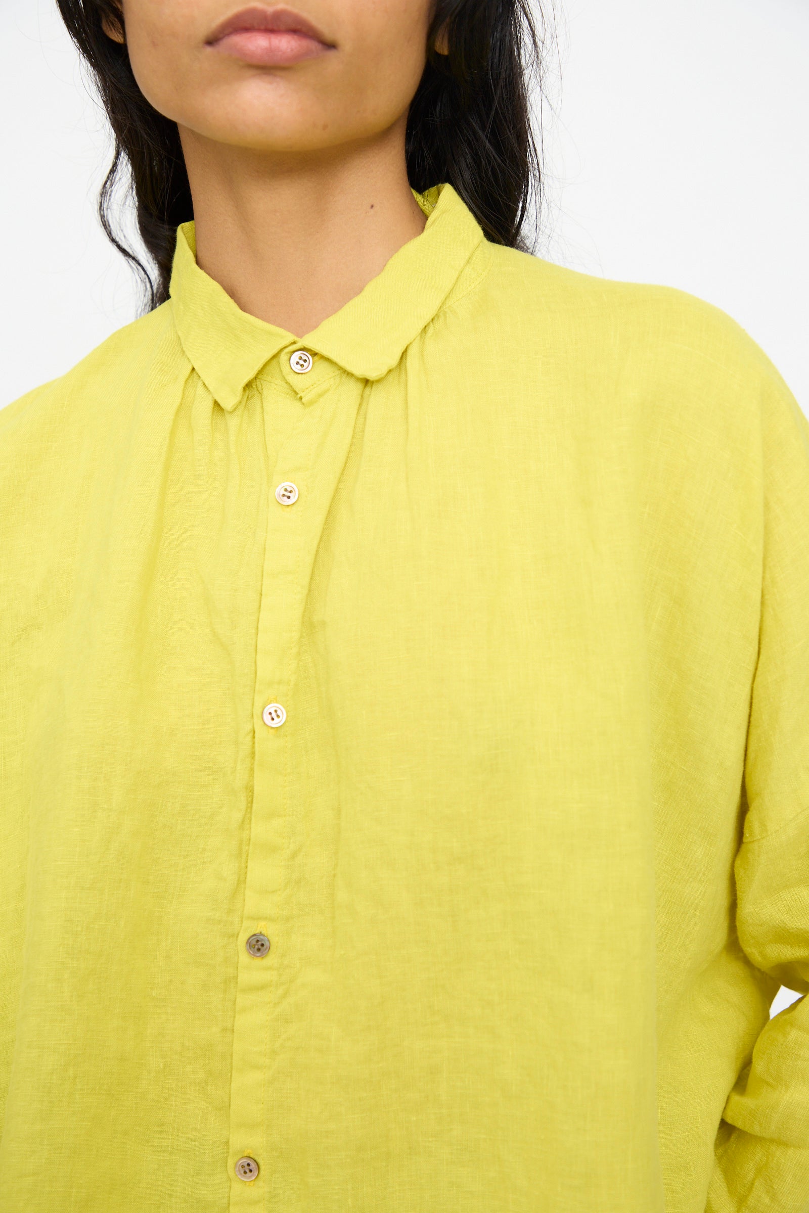 A person wears the Ichi Antiquités French Linen Shirt in Yellow, a button-up, long-sleeve shirt with a small collar made in Japan, shown from the chest up against a plain background.