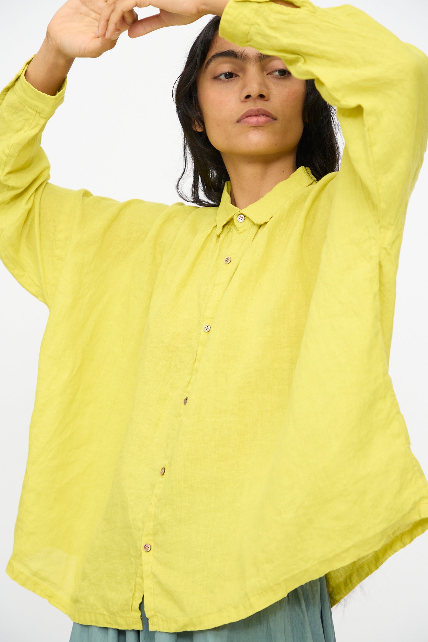 Model wears the Ichi Antiquités French Linen Shirt in Yellow, a loose-fitting Japanese-made long-sleeve top, raising both arms and looking to the side against a plain background.