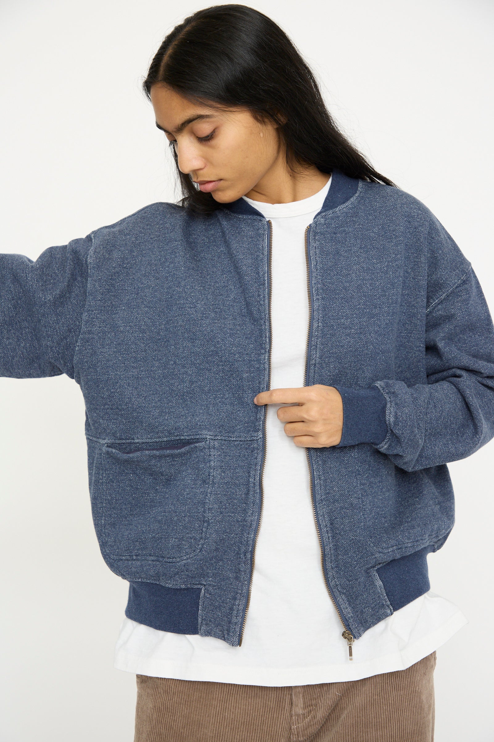 Someone in a relaxed-fit, French Terry Denim Blouson in Navy by Ichi Antiquités over a white shirt with brown pants looks down to the side.