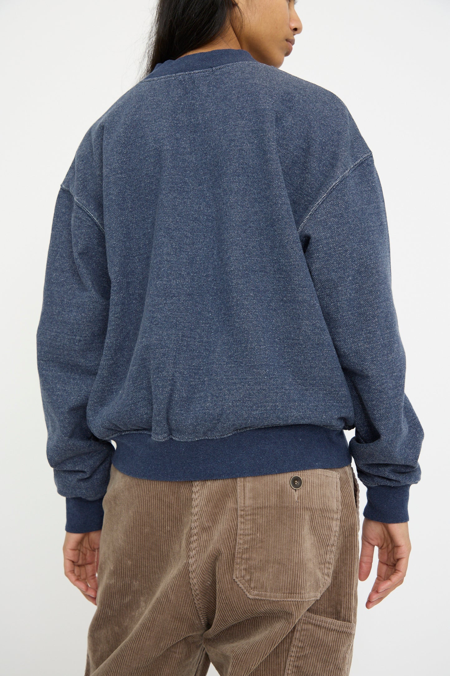 A person in a relaxed-fitting navy French Terry Denim Blouson by Ichi Antiquités and brown corduroy pants is shown from the back against a plain background.