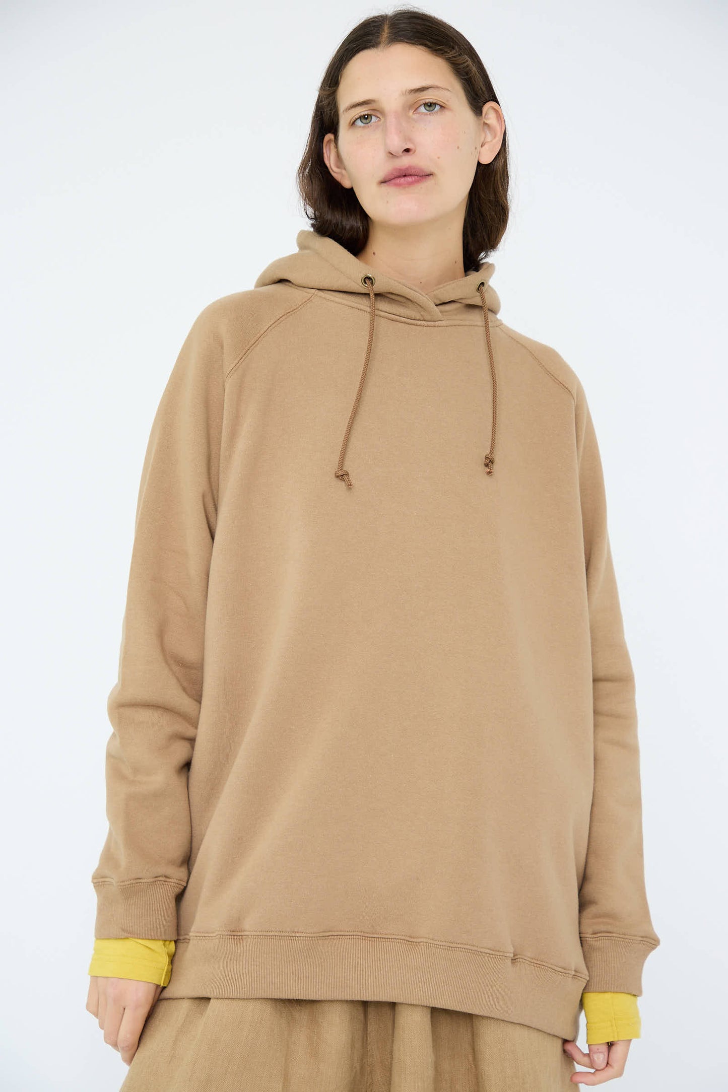 The individual is wearing the Ichi Antiquités French Terry Hoodie in Beige, featuring an oversized fit with yellow cuffs, crafted from soft cotton terry, and is standing against a plain background.