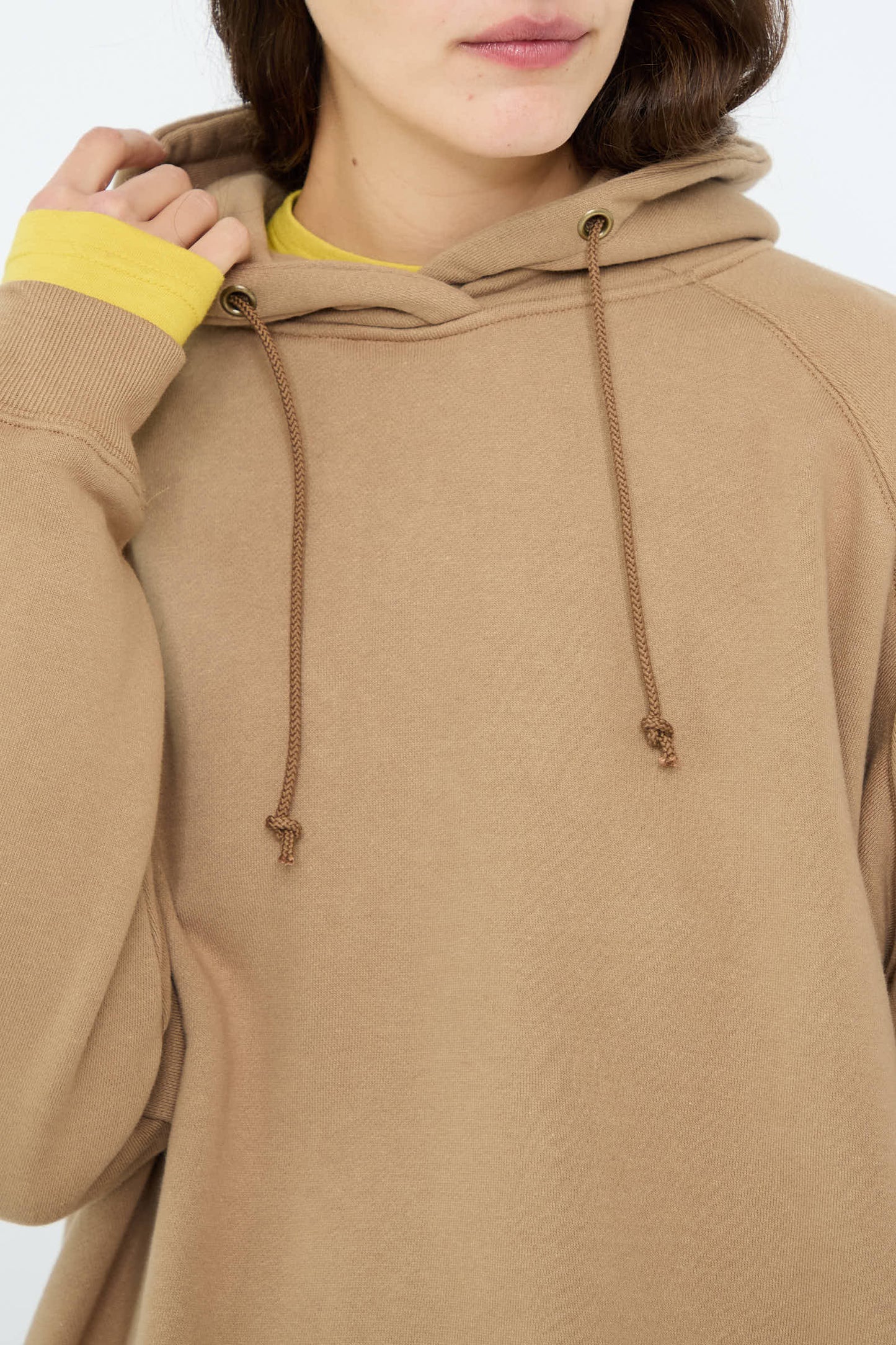 A person wearing the Ichi Antiquités French Terry Hoodie in Beige, featuring an oversized design with drawstrings, layered over a yellow shirt, is partially visible.