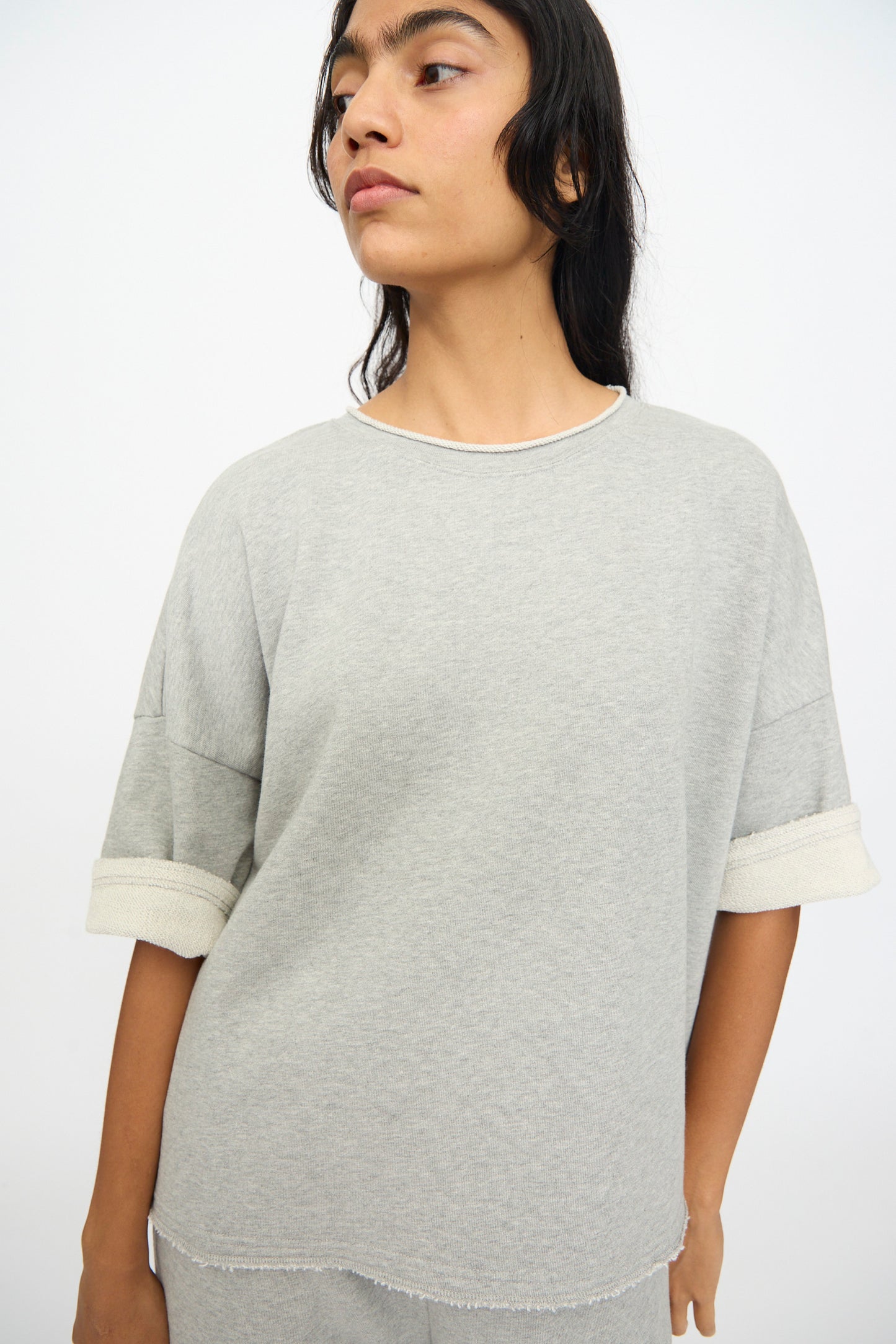Model wears the Ichi Antiquités French Terry Pullover in Gray— a loose-fitting, short sleeve cotton top with rolled cuffs and matching pants—standing against a plain white background.