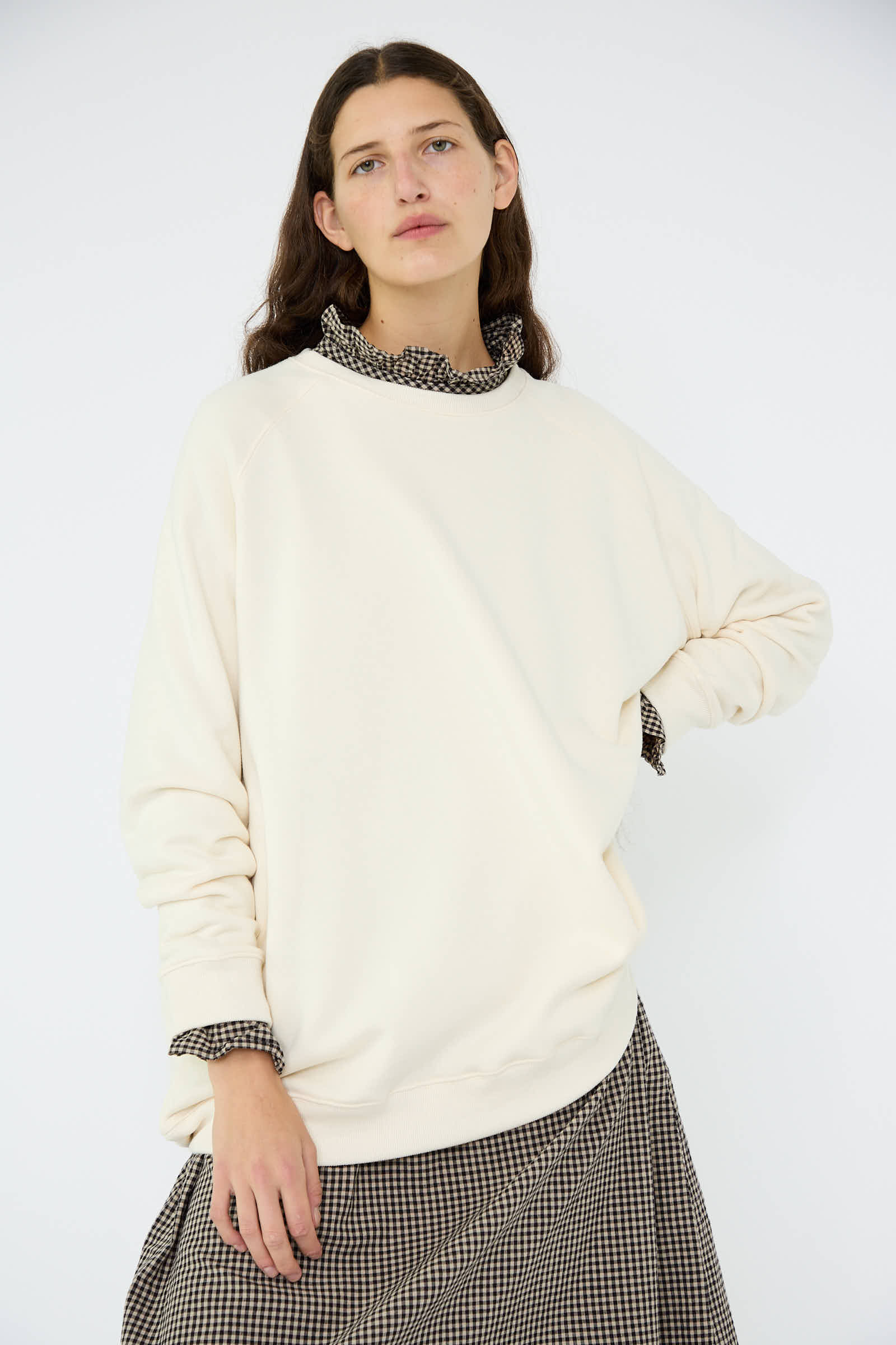 Wearing the French Terry Sweatshirt in Natural by Ichi Antiquités, an individual pairs it with a checkered collar underneath and a matching skirt, standing against a plain background.