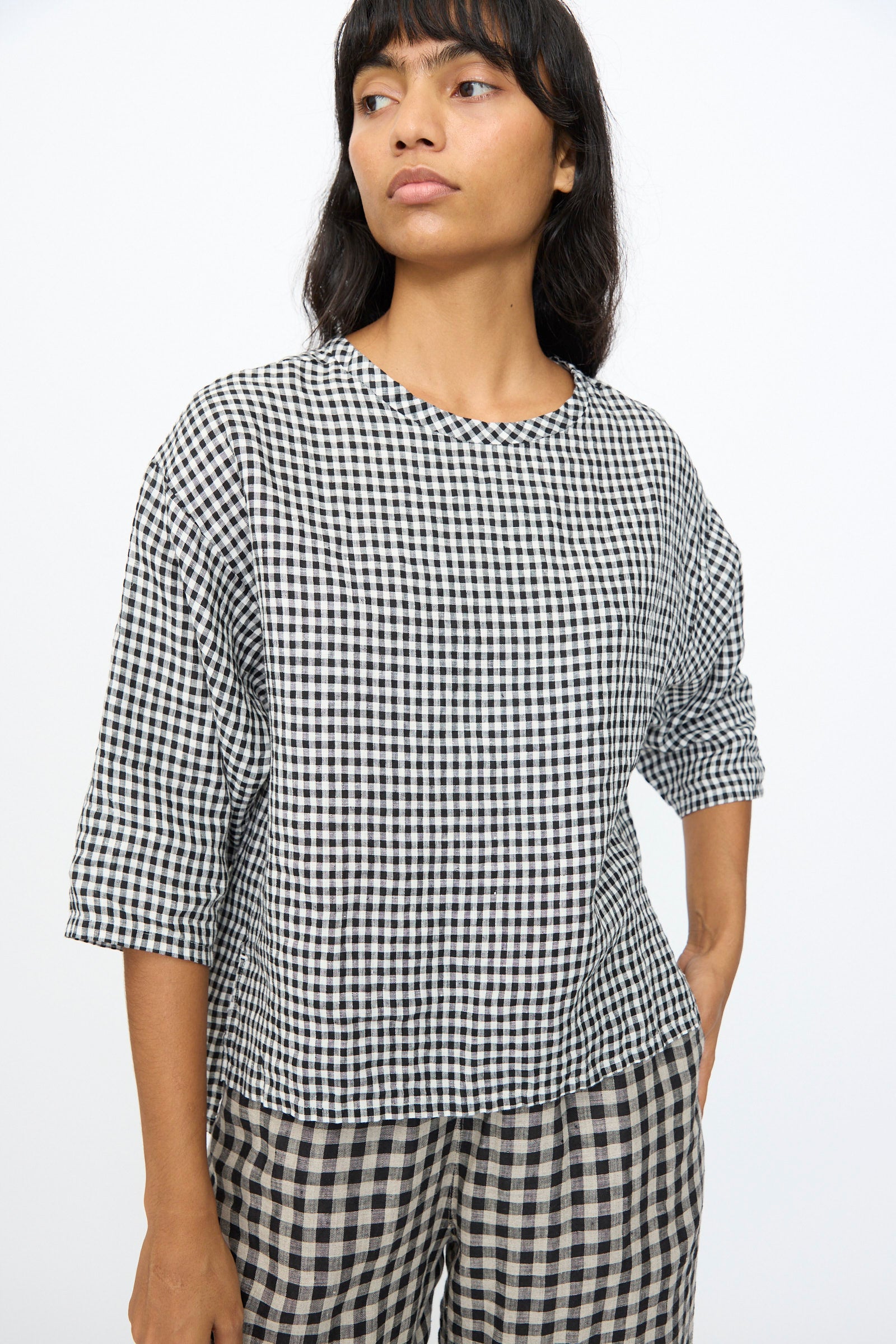 A person wears the Ichi Antiquités Gingham Check Blouse in White and Black, styled with matching checkered pants, standing against a plain white background.