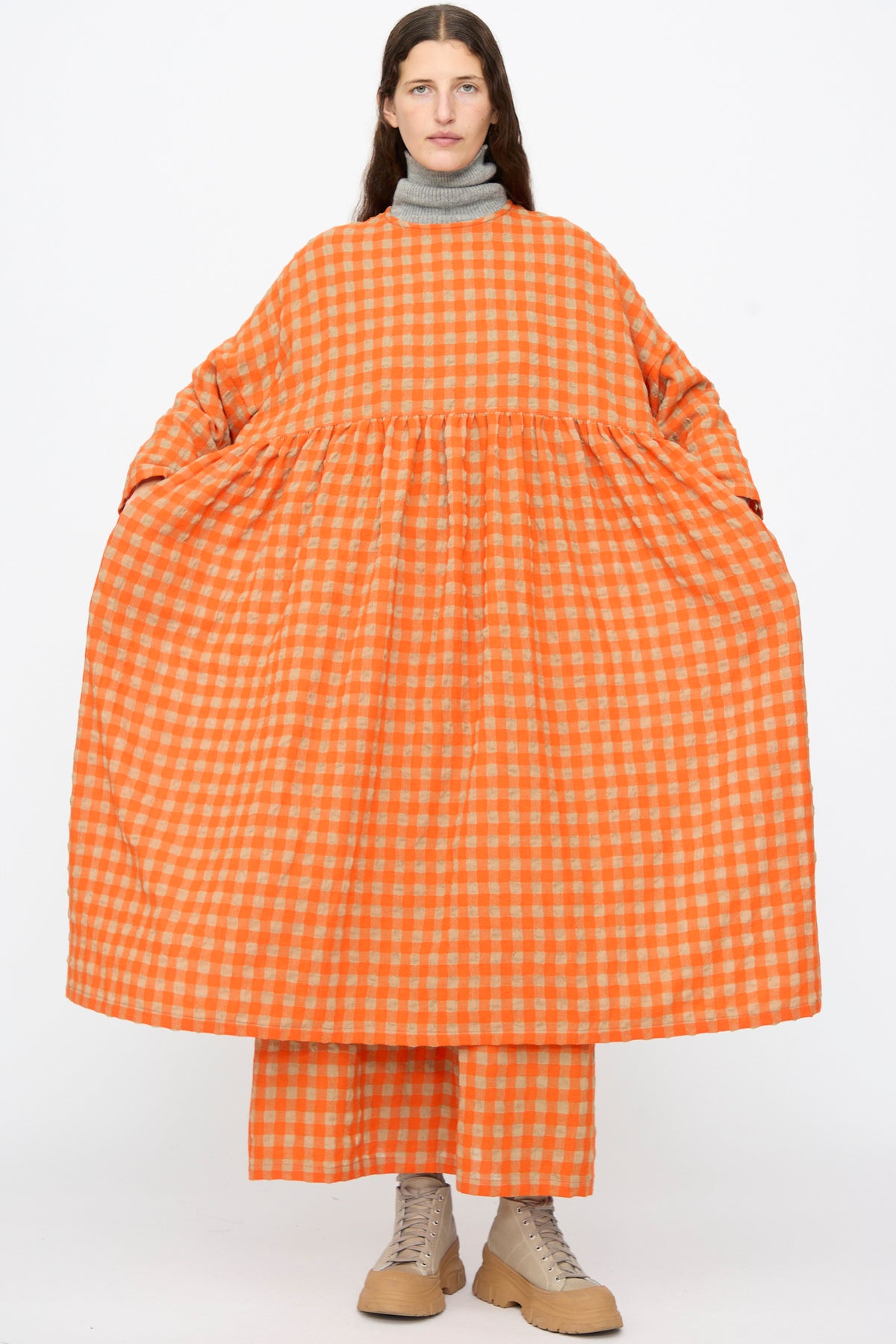 A person wearing an Ichi Antiquités Gingham Check Dress in Beige and Orange over matching trousers and beige platform sneakers.