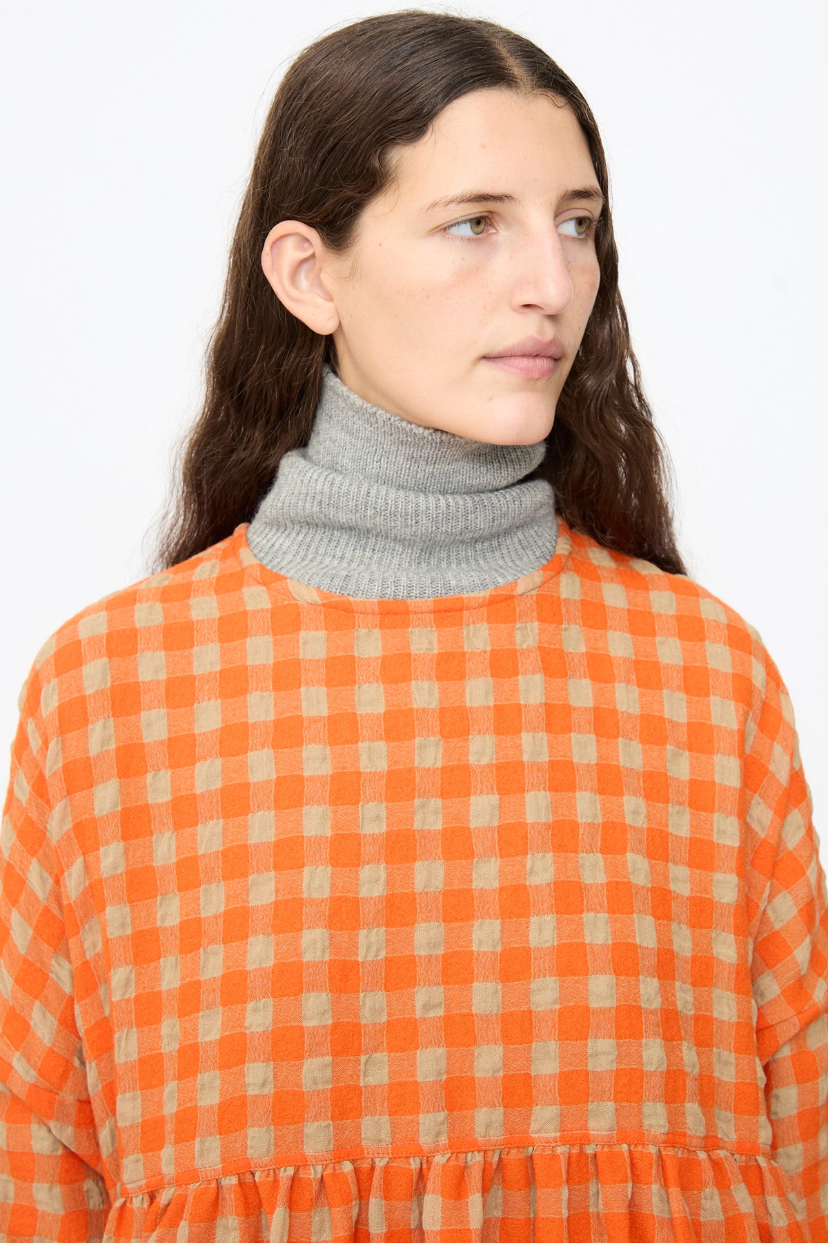 A person wearing an Ichi Antiquités Gingham Check Dress in Beige and Orange over a grey turtleneck.