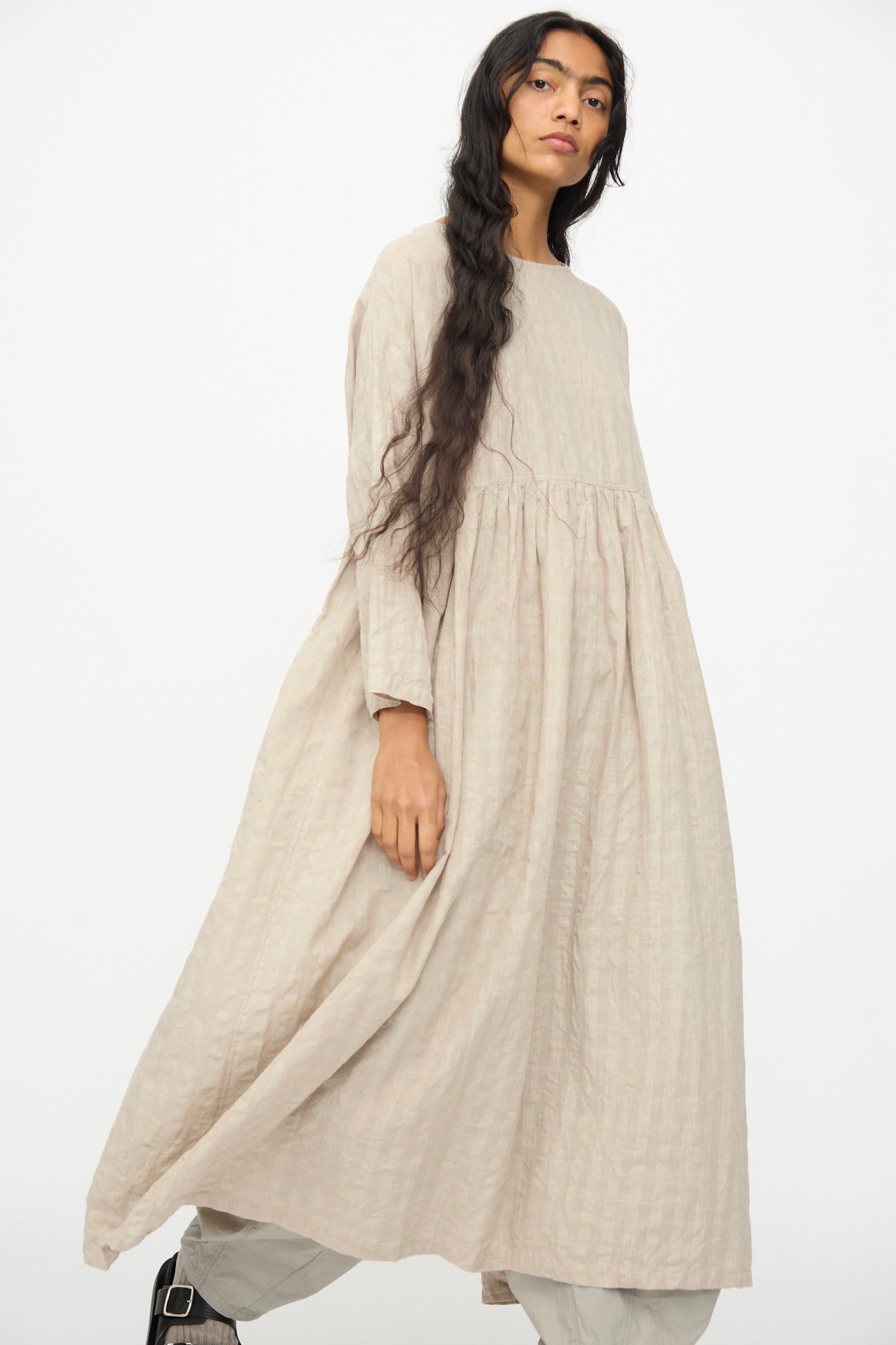 Person wearing the Gingham Check Dress in Natural by Ichi Antiquités, a loose-fit long sleeve dress made from a cotton-linen blend, displayed against a plain white background.