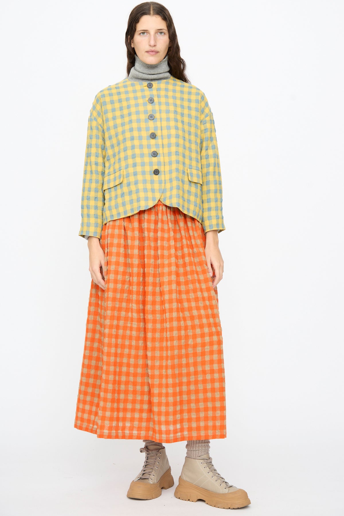 A person wears an Ichi Antiquités Gingham Check Jacket in Blue and Yellow over a grey turtleneck and an orange gingham maxi skirt, paired with tan lace-up boots.