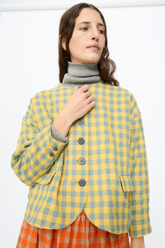 A model wears an Ichi Antiquités Gingham Check Jacket in Blue and Yellow over a grey turtleneck and an orange plaid skirt.