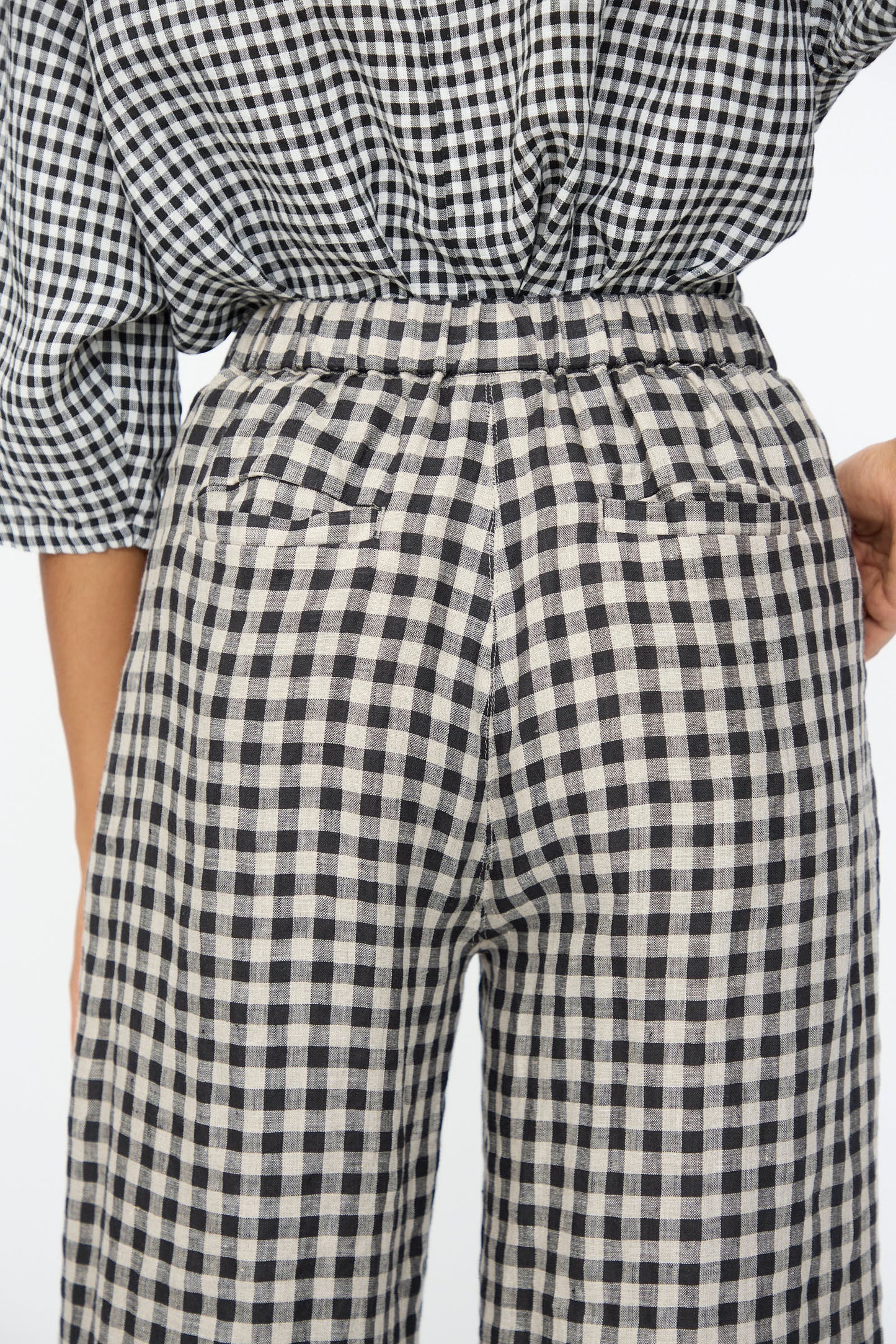 A person shown from the back wearing Ichi Antiquités Gingham Check Pants in Natural and Black with an elastic waistband and a matching checkered top.