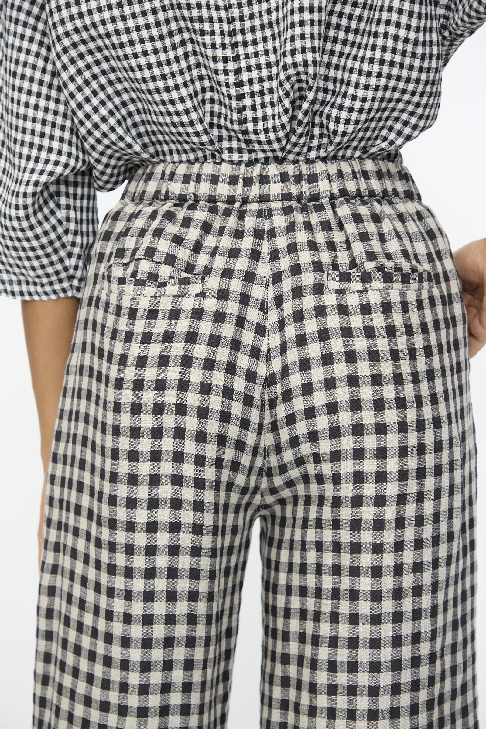 A person shown from the back wearing Ichi Antiquités Gingham Check Pants in Natural and Black with an elastic waistband and a matching checkered top.