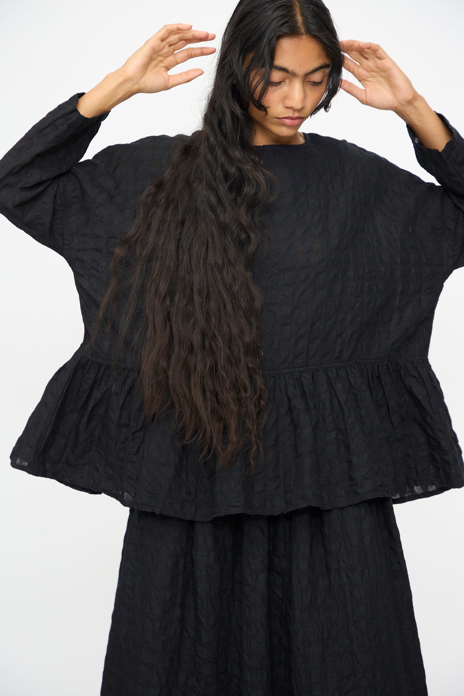 A person with long, wavy hair wears the Ichi Antiquités Gingham Check Pullover in Black, styled in a relaxed fit, standing against a plain white background.