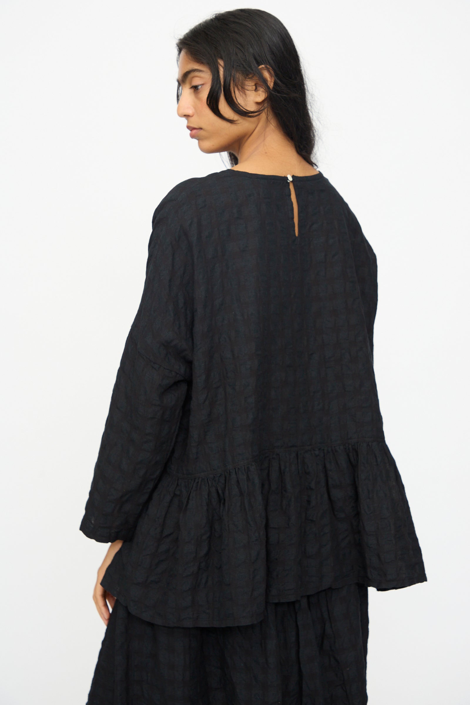 A woman with long dark hair, wearing the Ichi Antiquités Gingham Check Pullover in Black, stands against a plain white background.
