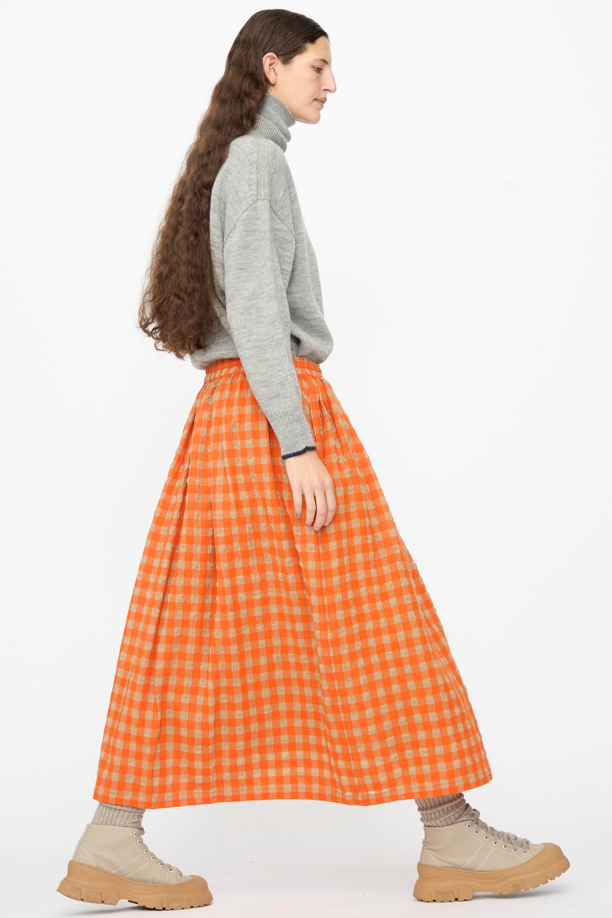 A person wears a grey turtleneck sweater with an Ichi Antiquités Gingham Check Skirt in Beige and Orange, paired with beige lace-up boots.