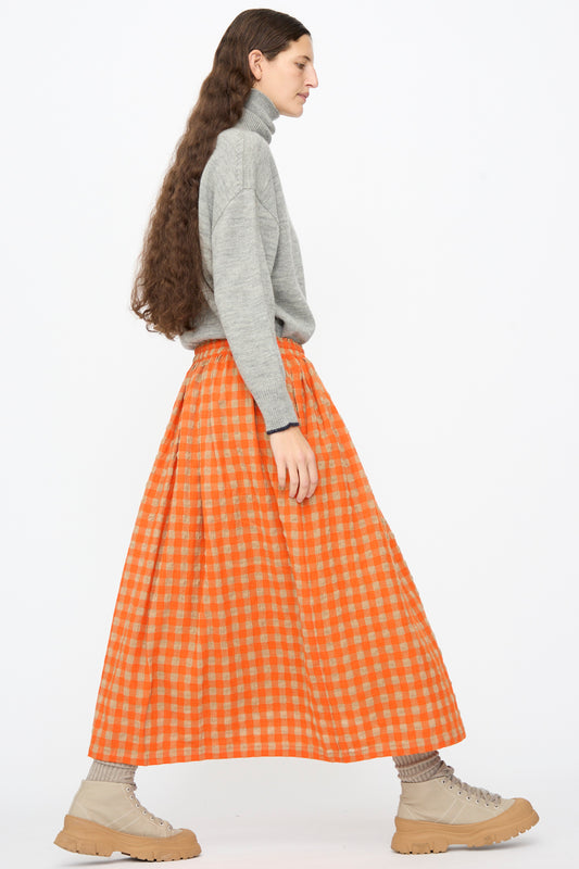A person wears a grey turtleneck sweater with an Ichi Antiquités Gingham Check Skirt in Beige and Orange, paired with beige lace-up boots.