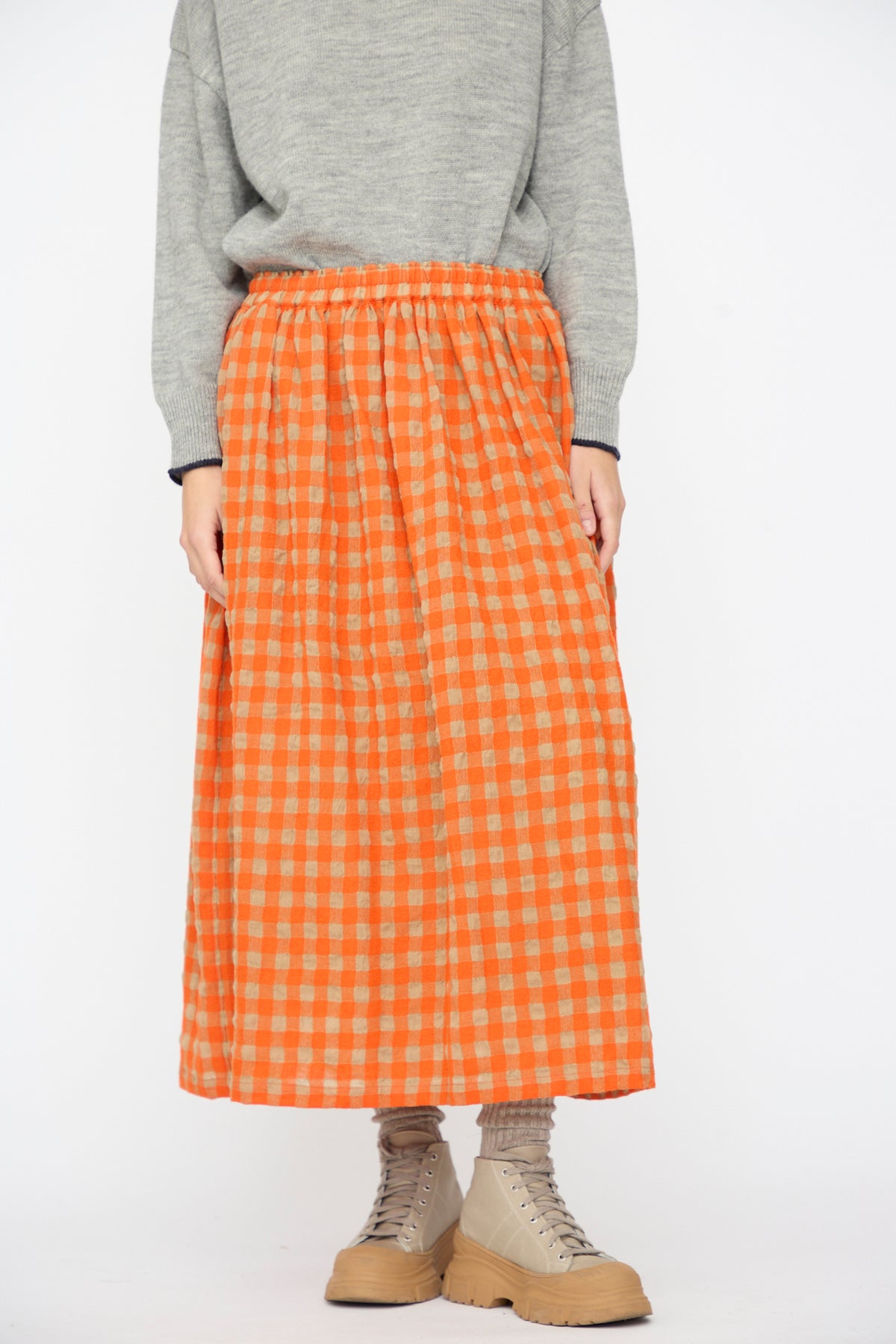 Ichi Antiquités Gingham Check Skirt in Beige and Orange, an A-line midi skirt with an elastic waistband, worn with a gray sweater and lace-up boots.